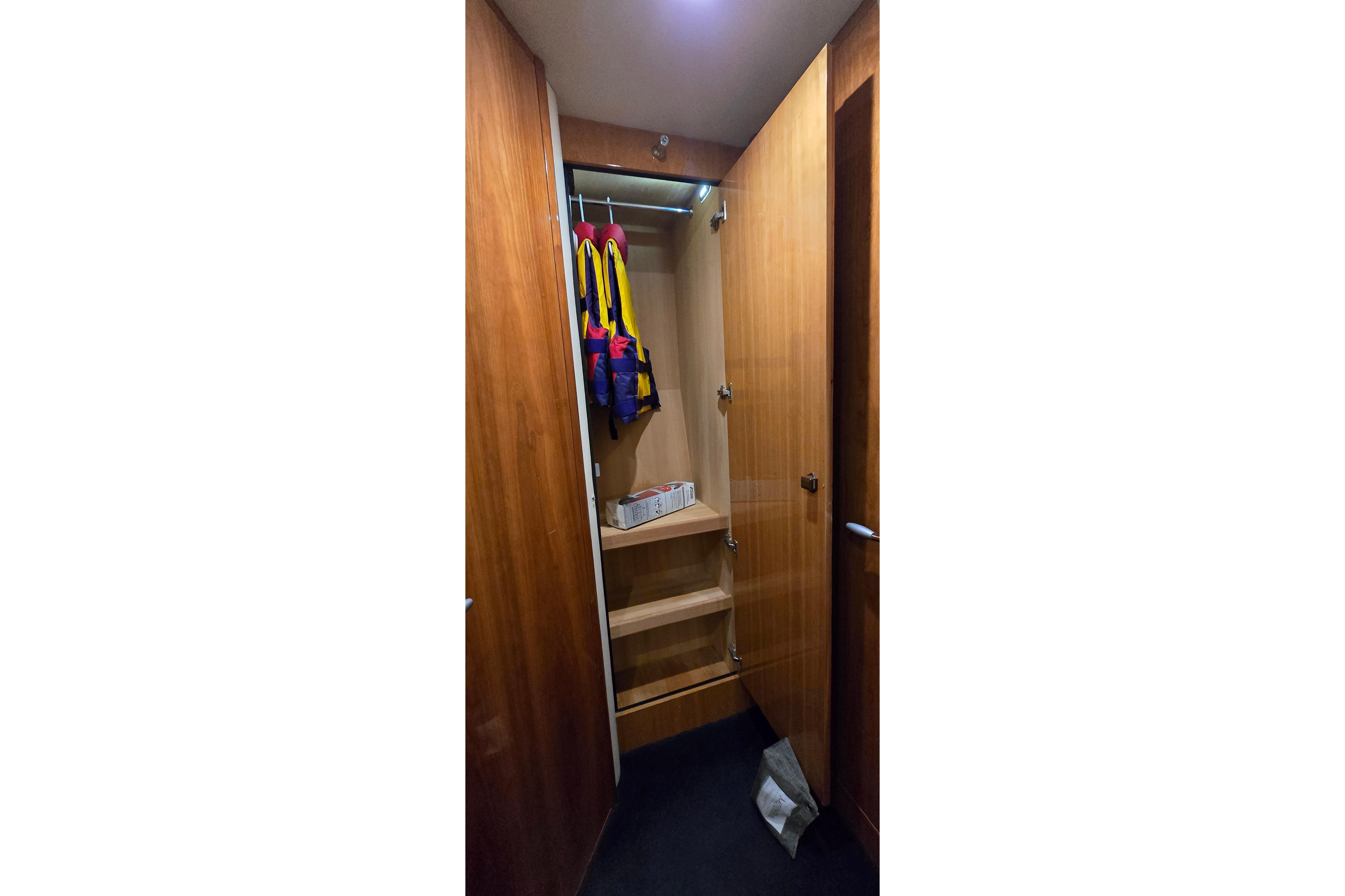 Wooden closet interior on 2004 Sunseeker Camargue 50 yacht, featuring life jackets and shelves.