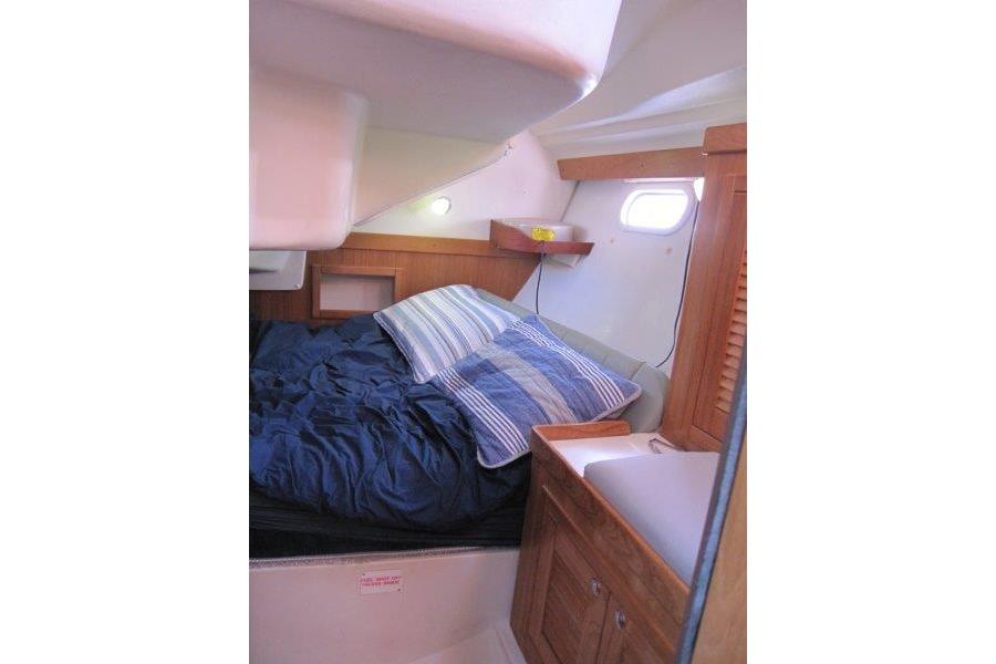 Cozy cabin interior of 2004 Catalina 350 MkII sailboat with bed and wooden cabinetry.