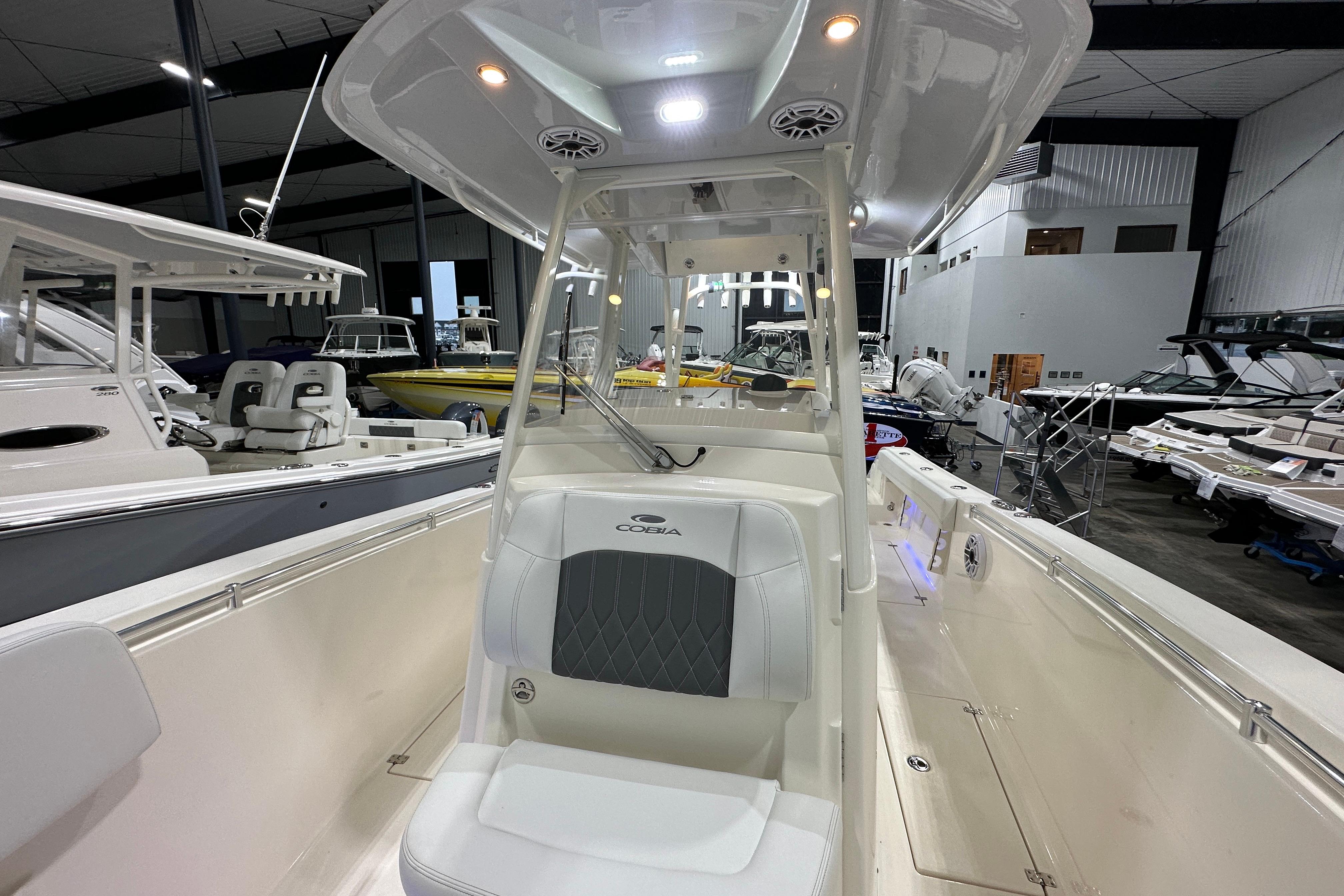 2024 Cobia 301 Center Console boat interior in showroom, showcasing seating and helm area.