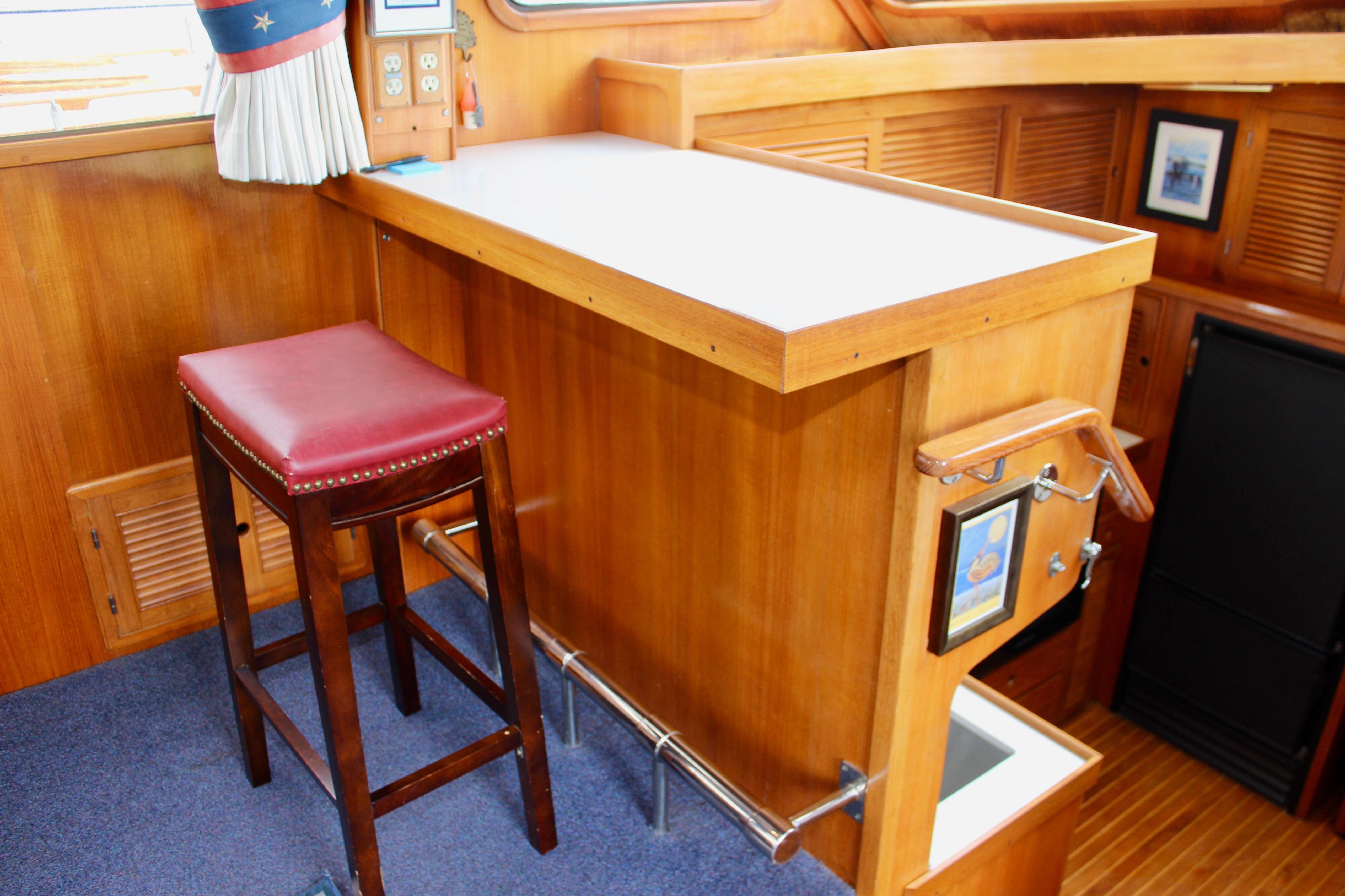 Interior of 1986 Kha Shing Spindrift 46 yacht with wooden bar and red stool.