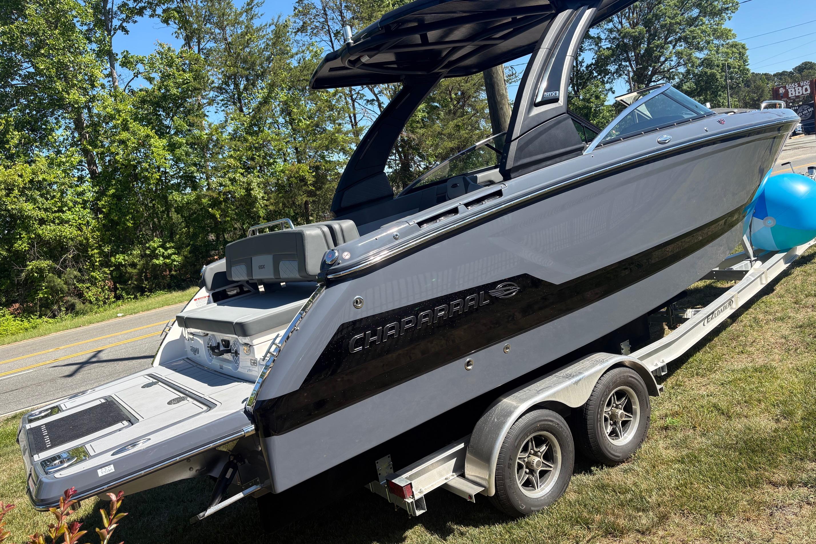 2025 Chaparral 2870 SSX boat on trailer, parked roadside with trees in background.