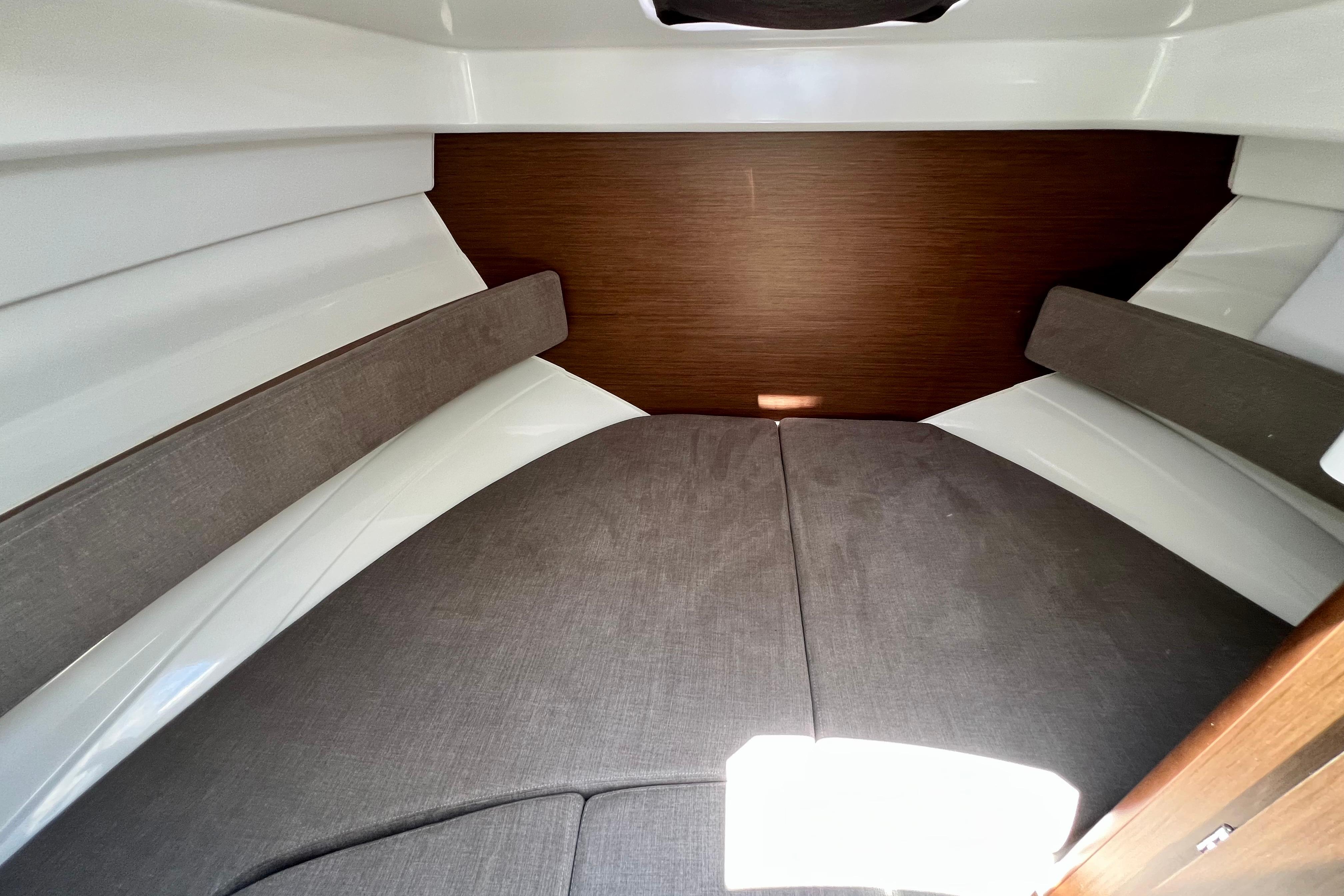 2023 Beneteau Antares 8 cabin interior with cozy gray cushions and wooden accents.
