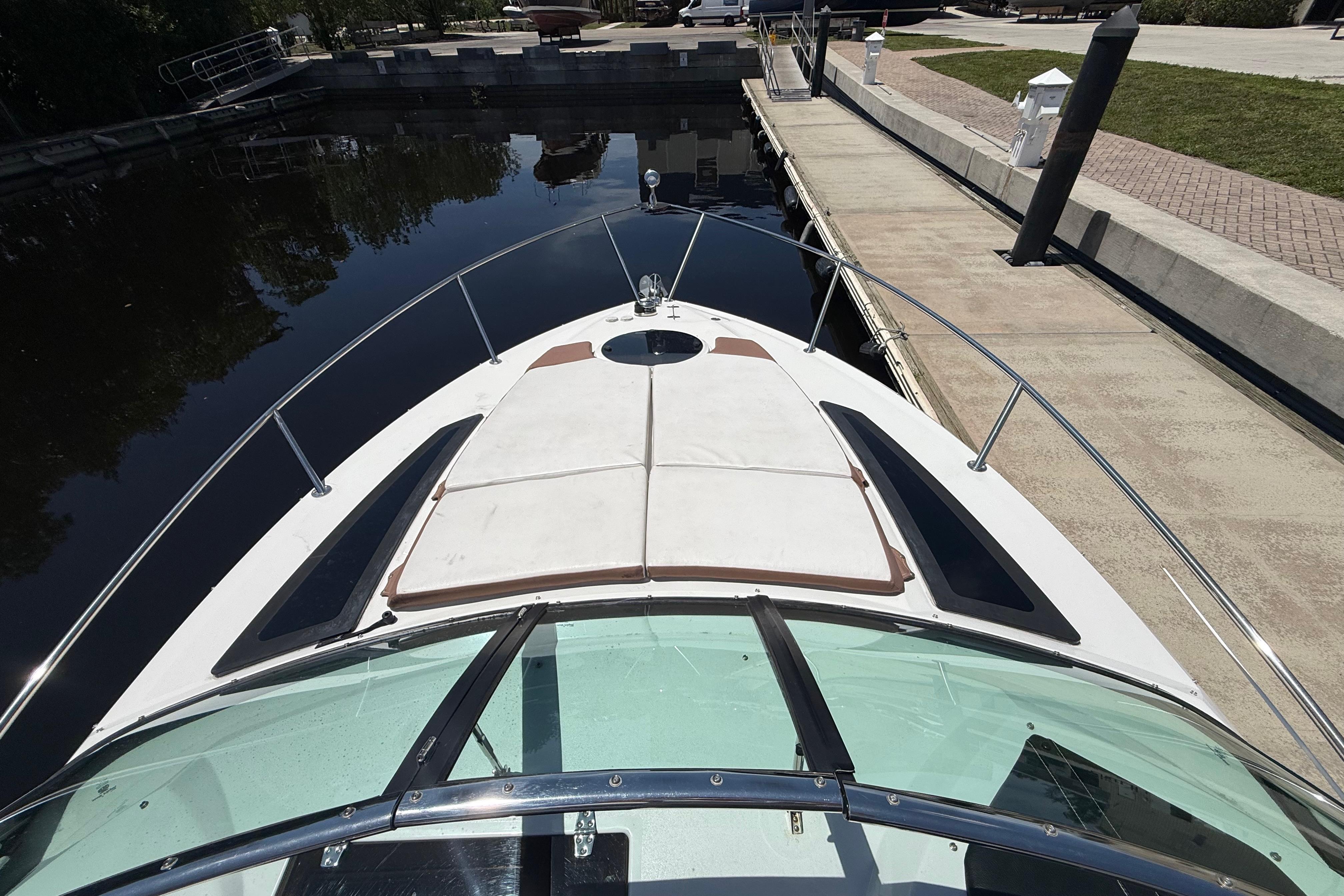 2017 Four Winns V275 boat docked, viewed from the bow, with sunpad and railing.