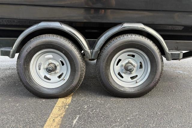 Trailer wheels of a 2017 Searay SPX210 boat on asphalt pavement.