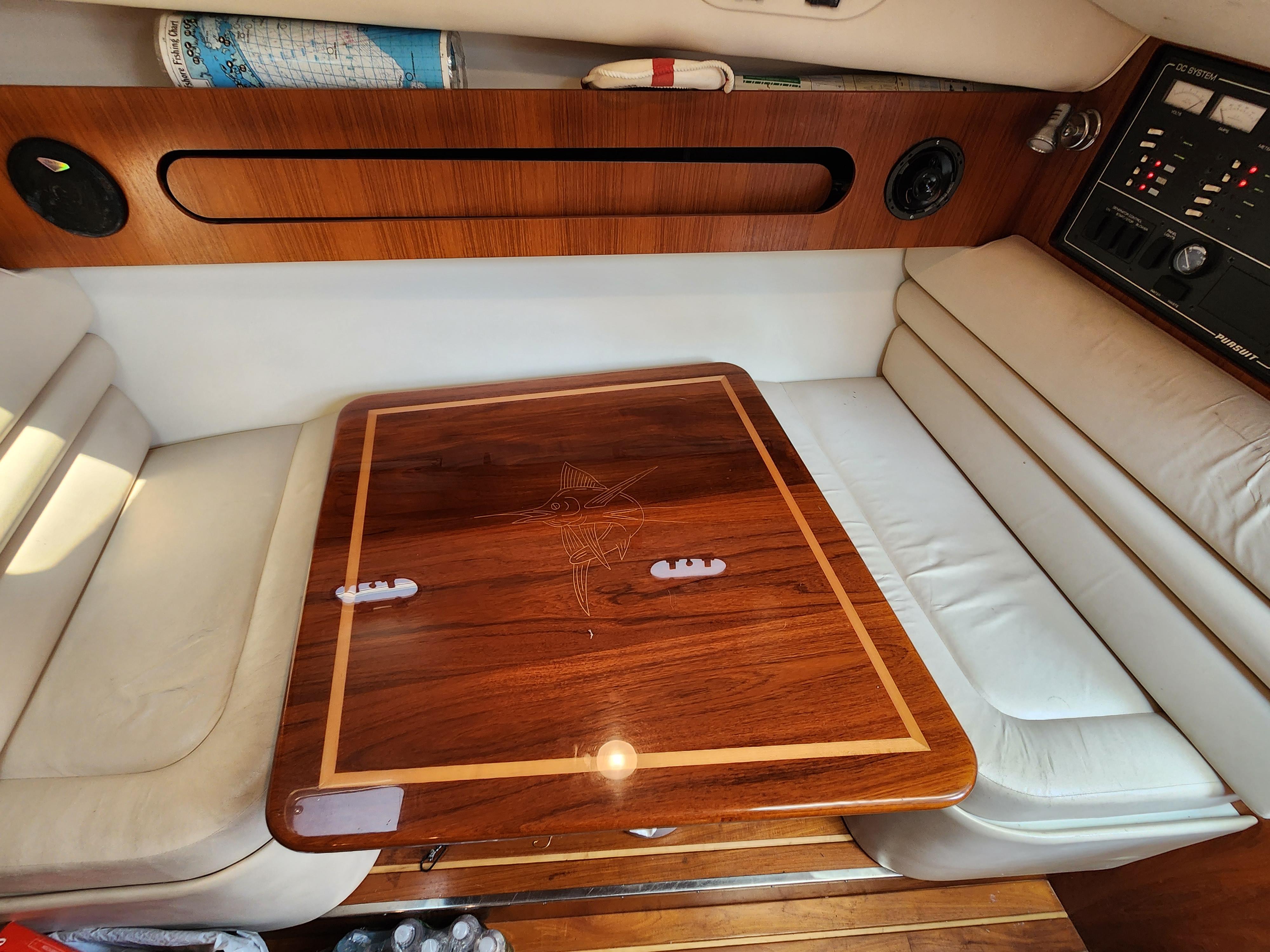 Interior of a 2000 Pursuit 3400 Express boat with a wooden table and white seating.