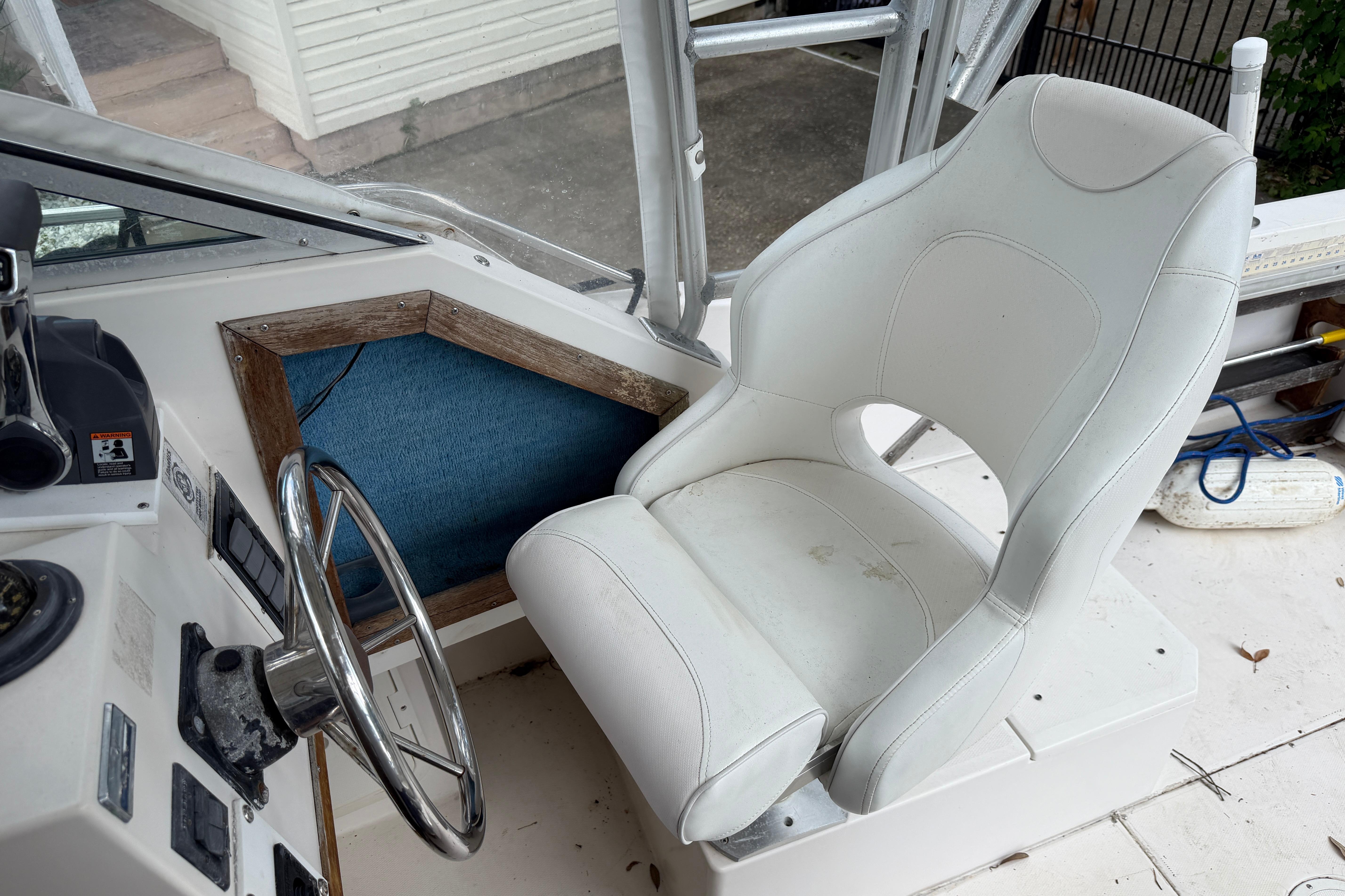 Interior of 1987 Grady-White Seafarer 226 boat with steering wheel and white captain's chair.