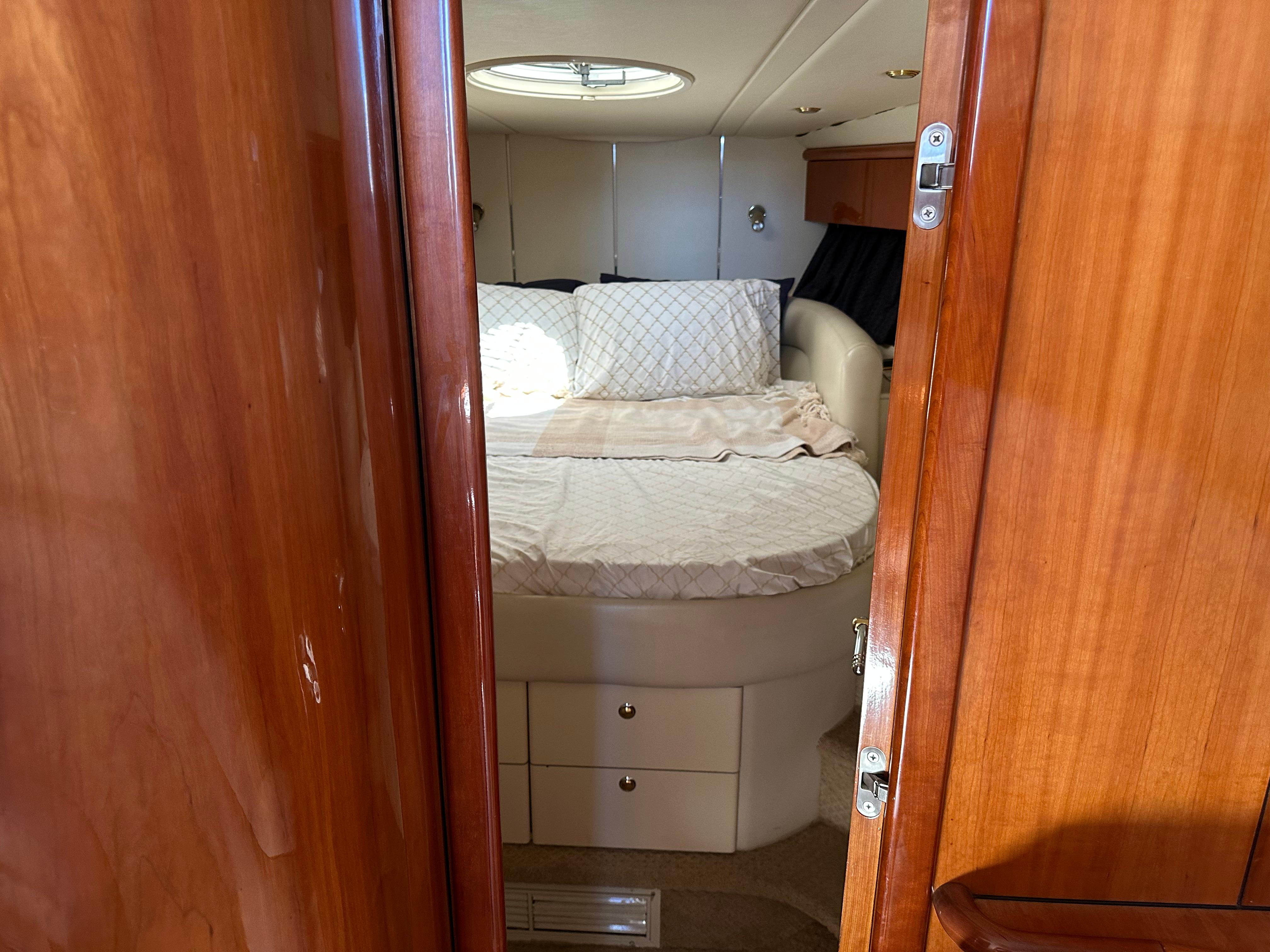 Cozy bedroom interior of 1997 Sunseeker Camargue 47 yacht with wooden door and round bed.