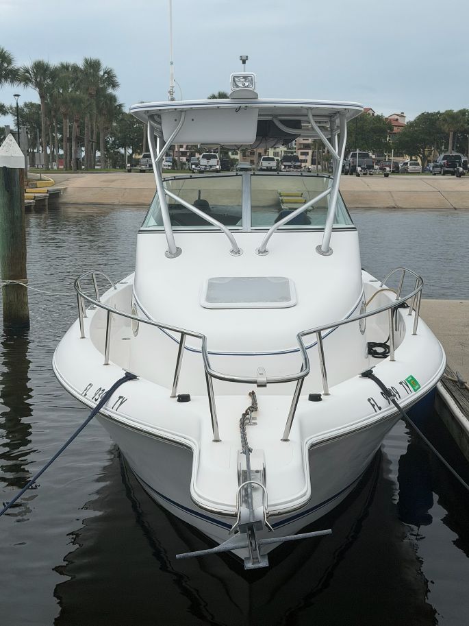 A white boat with a covered helm is docked at a pier.