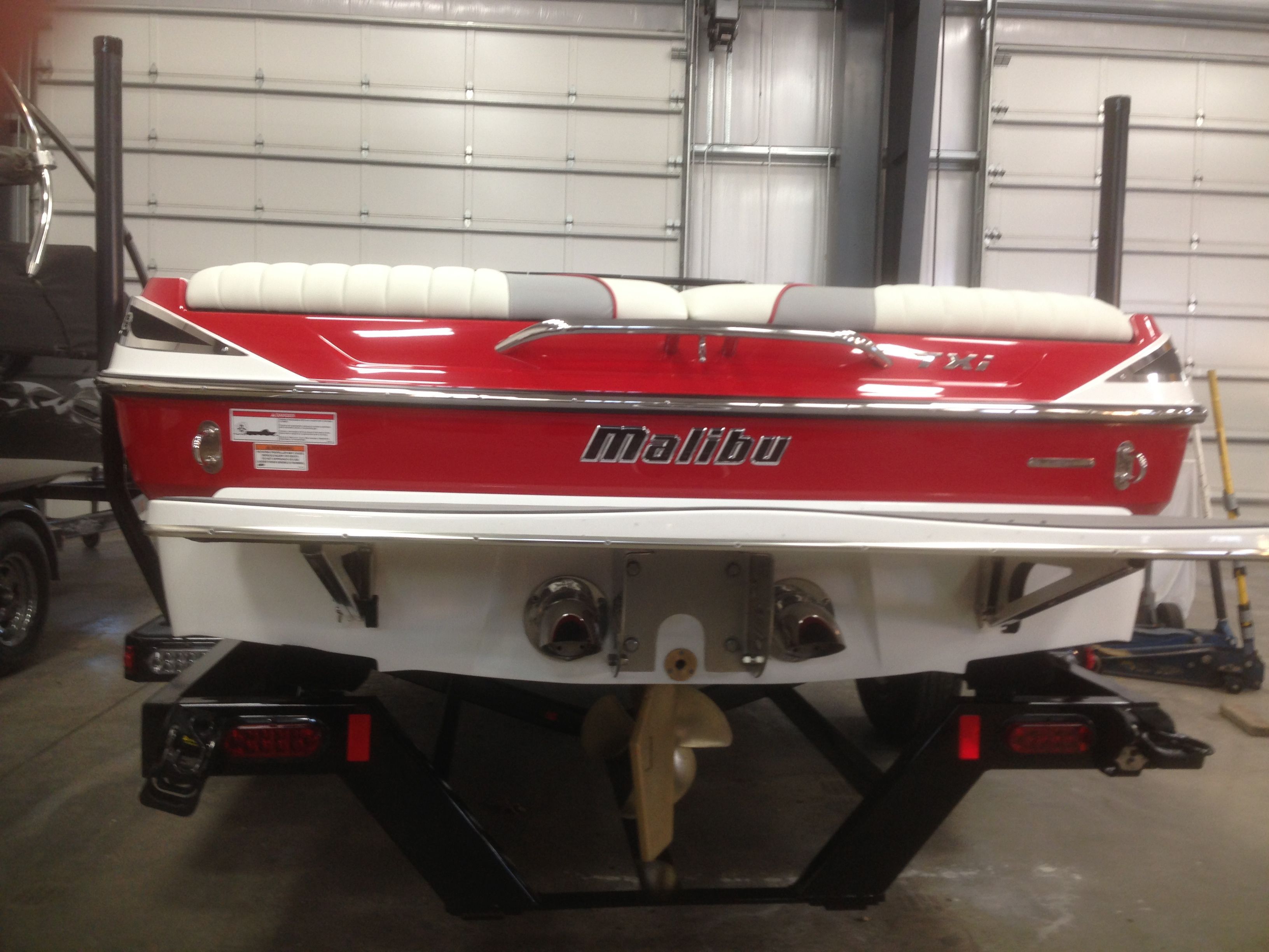 Red 2014 Malibu Response TXi boat in a garage.