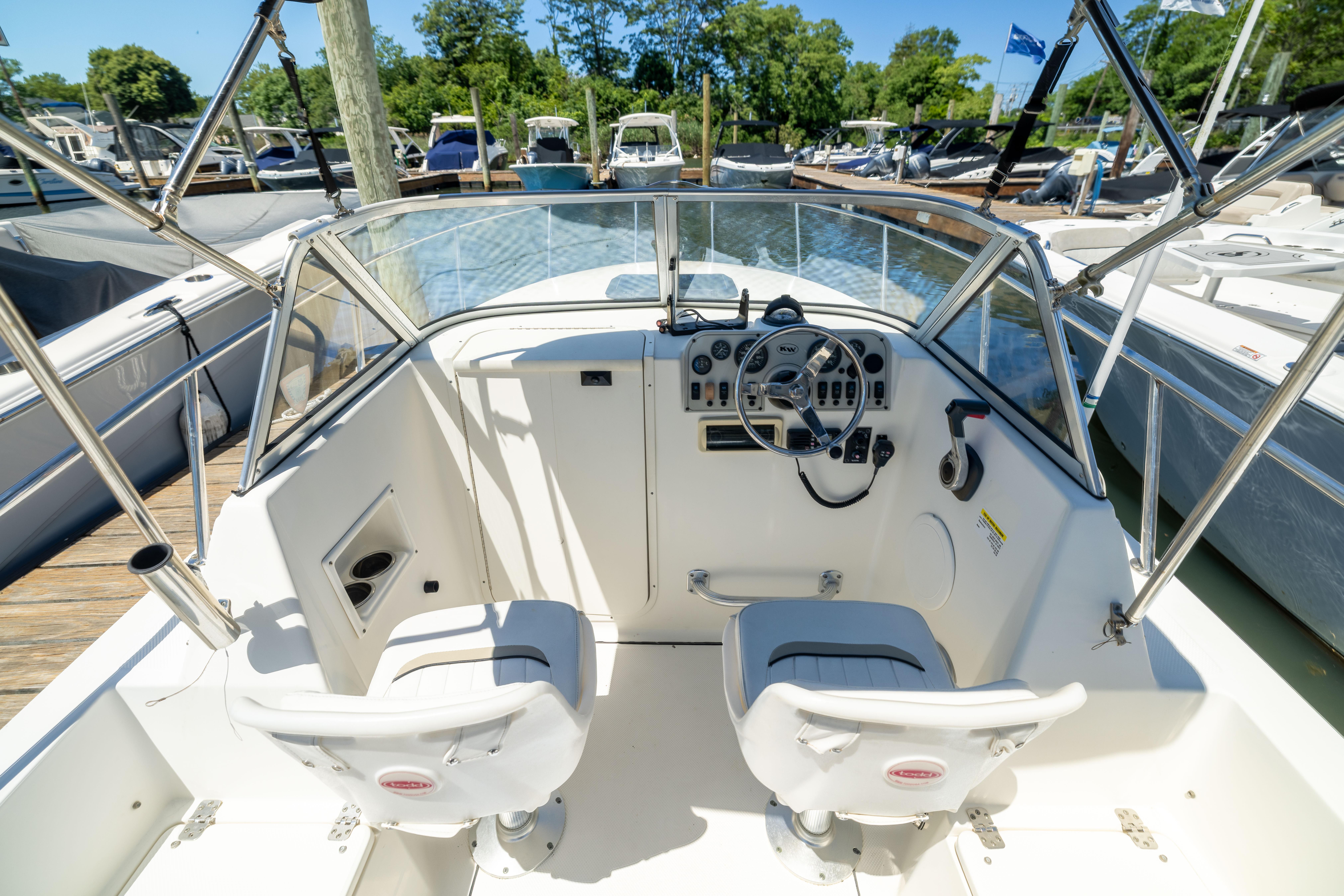 Cockpit of 2012 KEYWEST 2020 WA boat, featuring dual seats and steering controls at a marina.