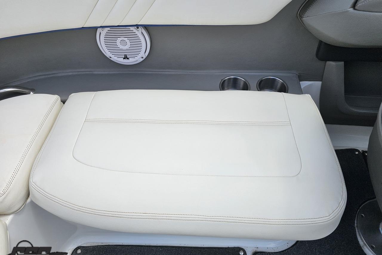 2010 Cobalt 232 WSS boat interior with white cushioned seating and built-in cup holders.