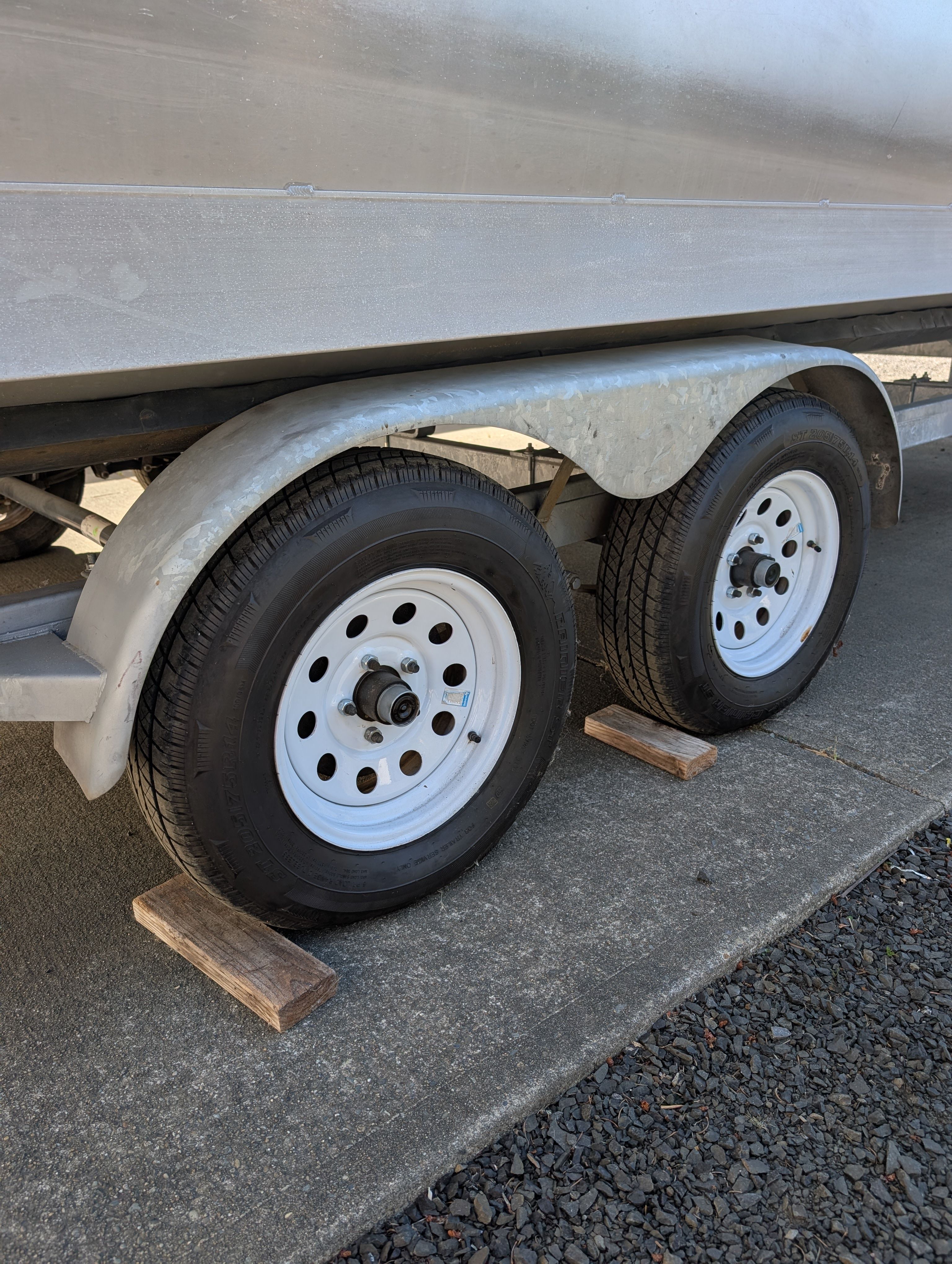 Close-up of a boat trailer with two tires on wooden blocks.