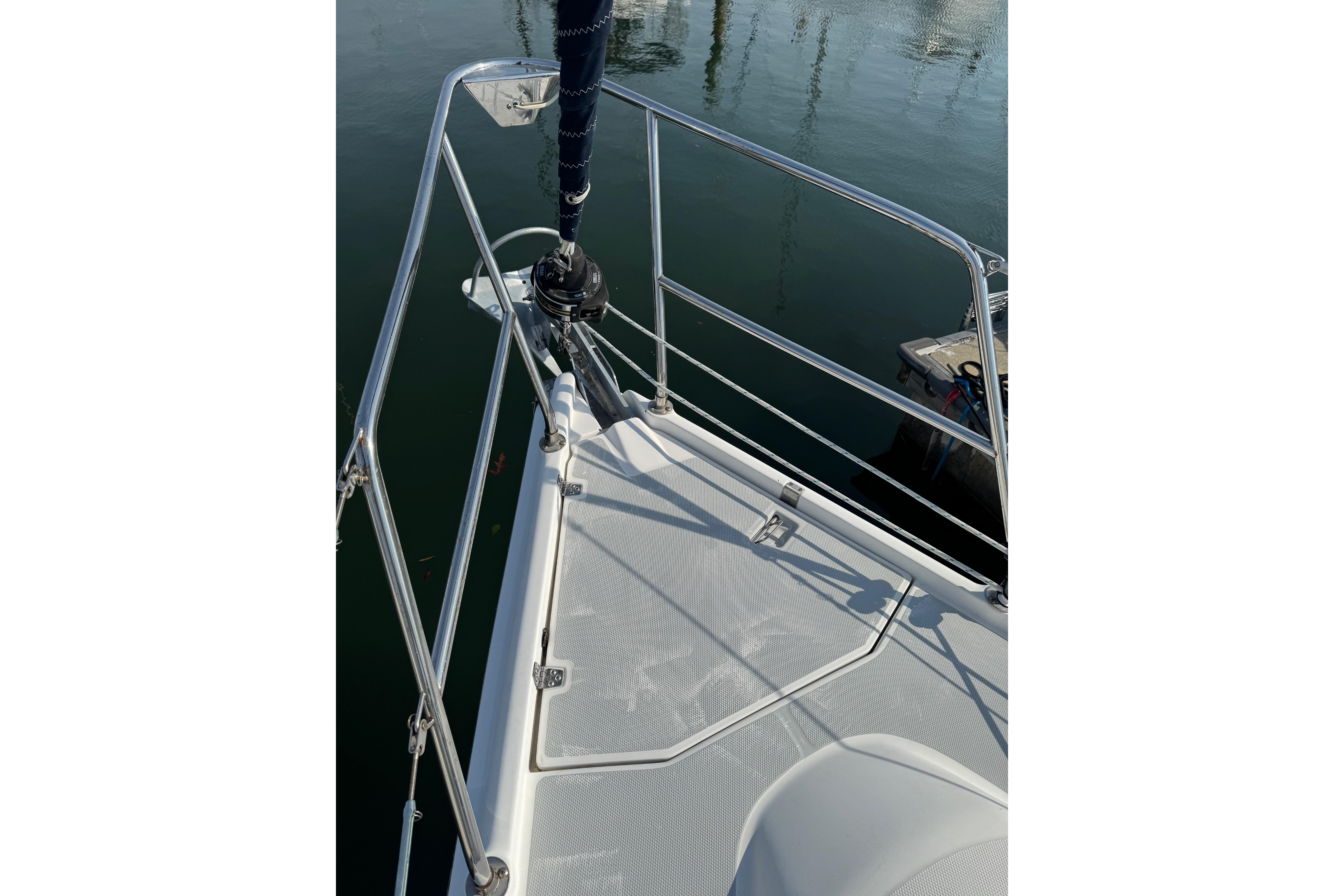 Bow of a 2002 Hunter 326 sailboat with stainless steel railings and calm water reflection.