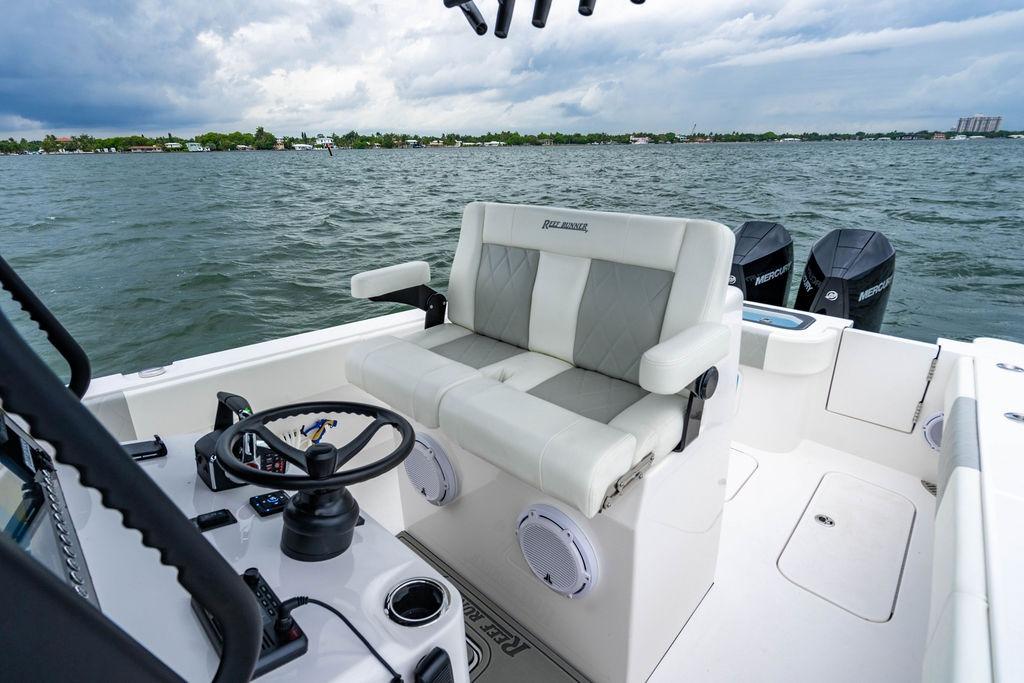 Modern Reef Runner 280 boat interior with dual engines, steering wheel, and cushioned seating, 2027 model.