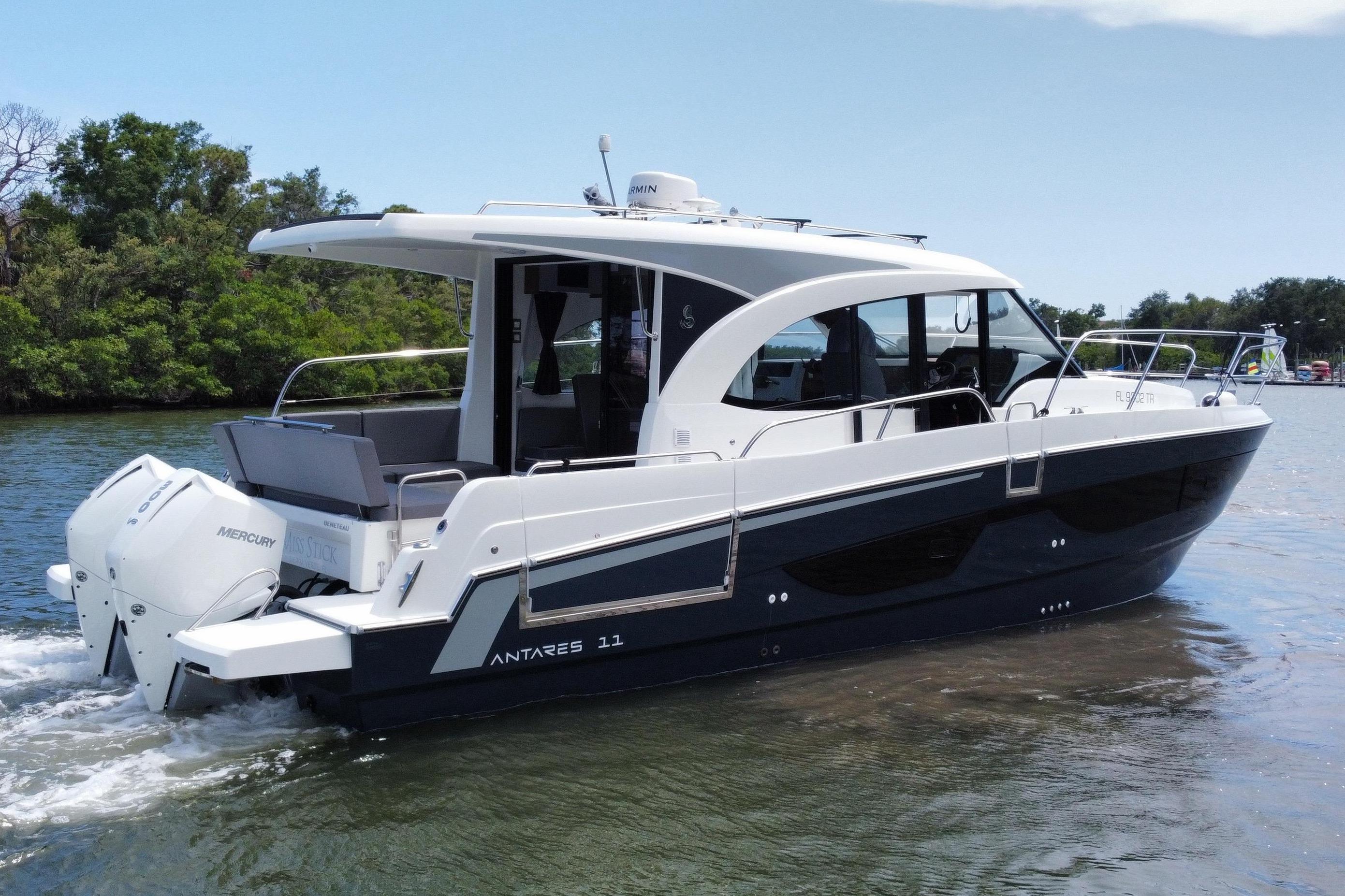 A 2024 Beneteau Antares 11 boat cruising on calm water with lush shoreline in the background.