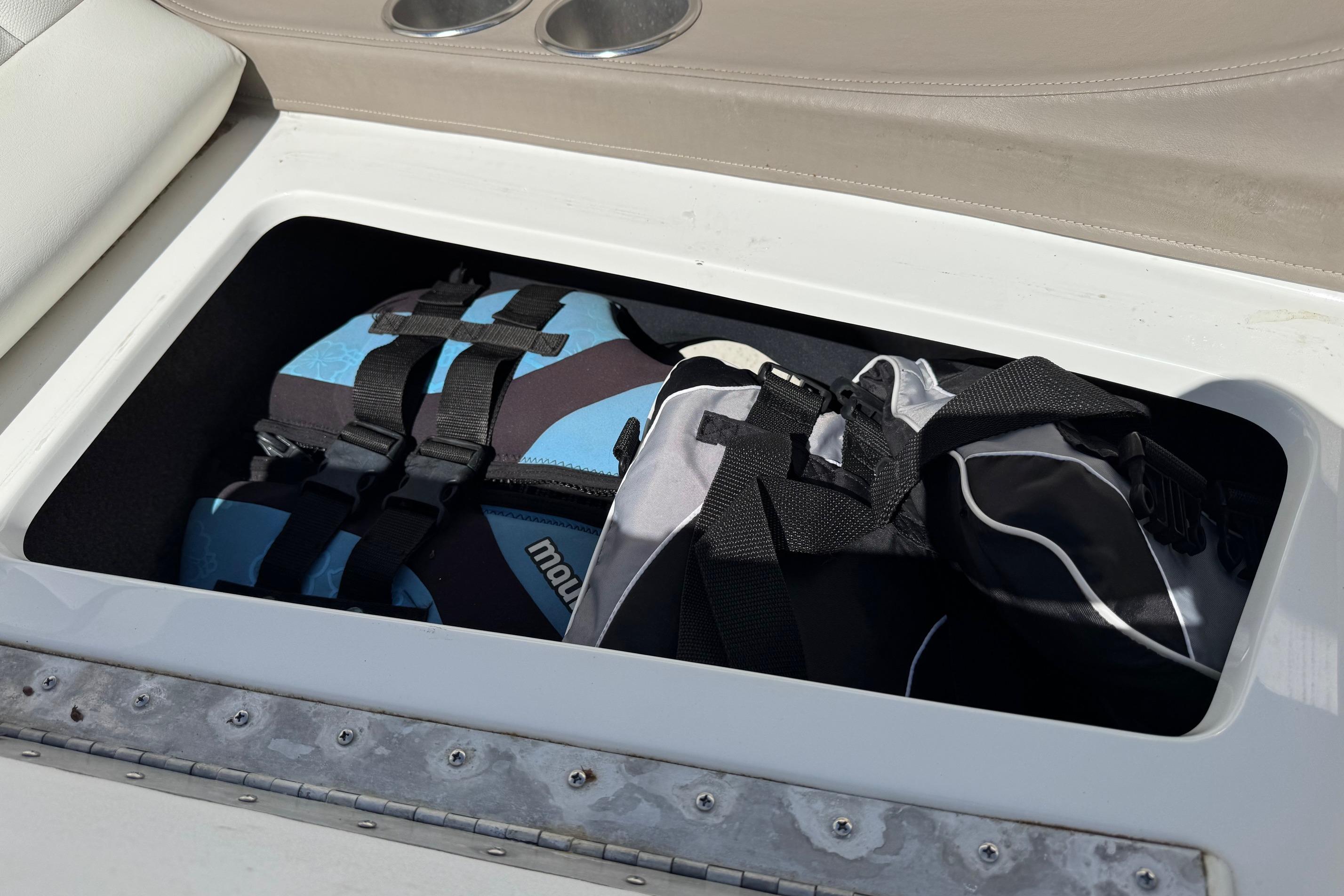 Storage compartment in a 2005 Cobalt 240 boat with life jackets inside.