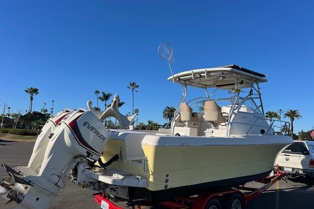 1998 Pro-Line 2610 Walkaround boat with Evinrude motor on trailer, parked outdoors.