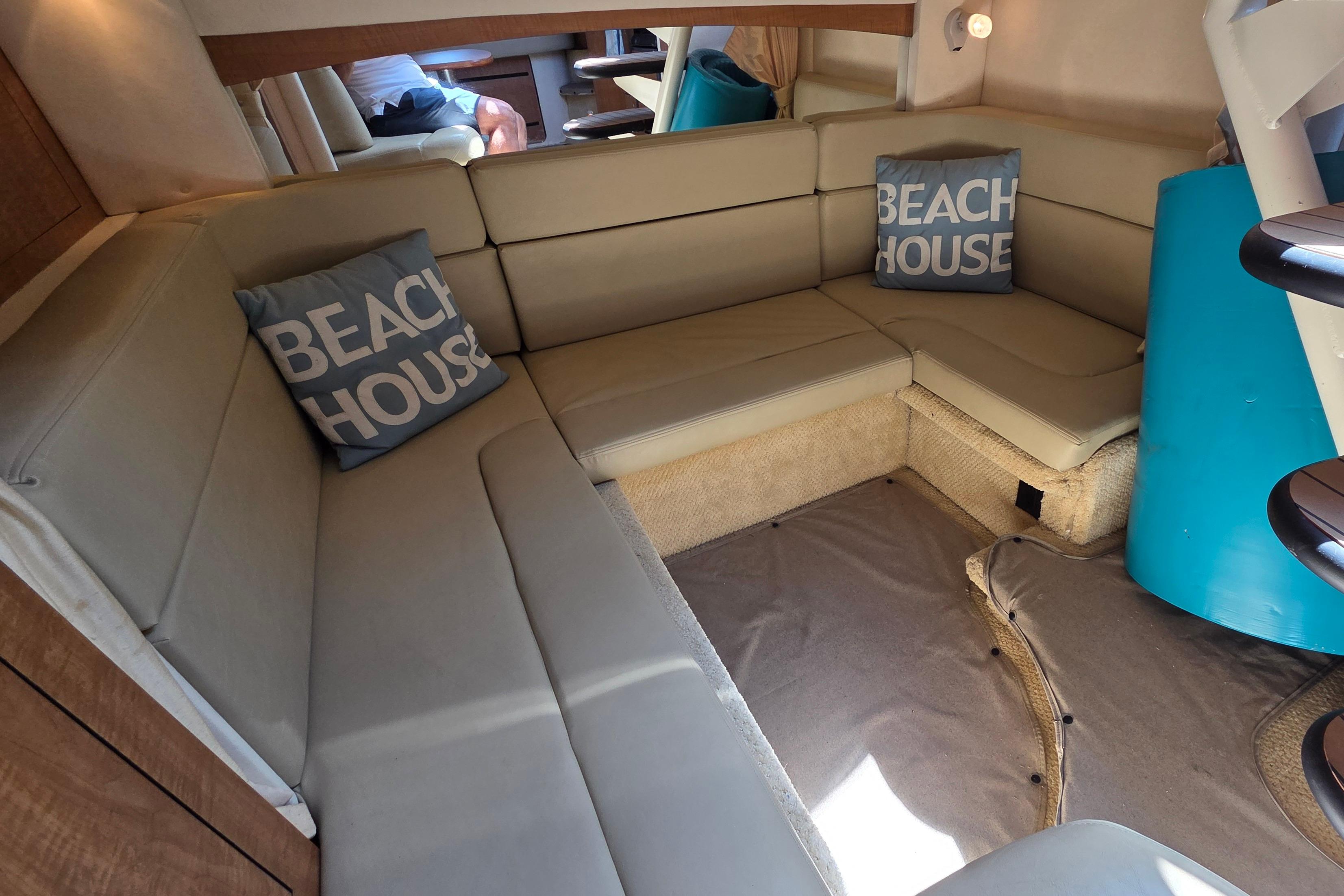 Interior of 2006 Sea Ray Sundancer 320 with beige seating and "Beach House" pillows.