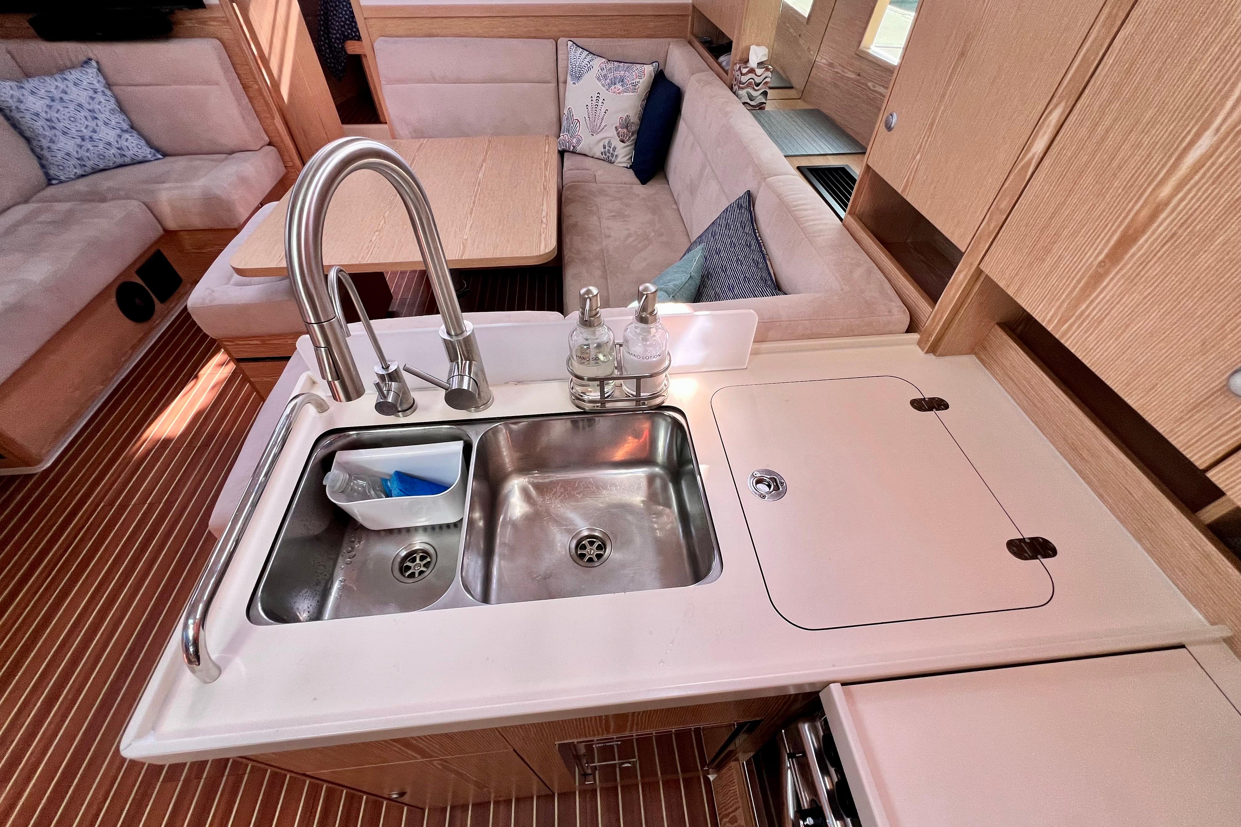 Modern kitchen area in a 2016 Hanse 455 yacht, featuring a double sink and cozy seating.