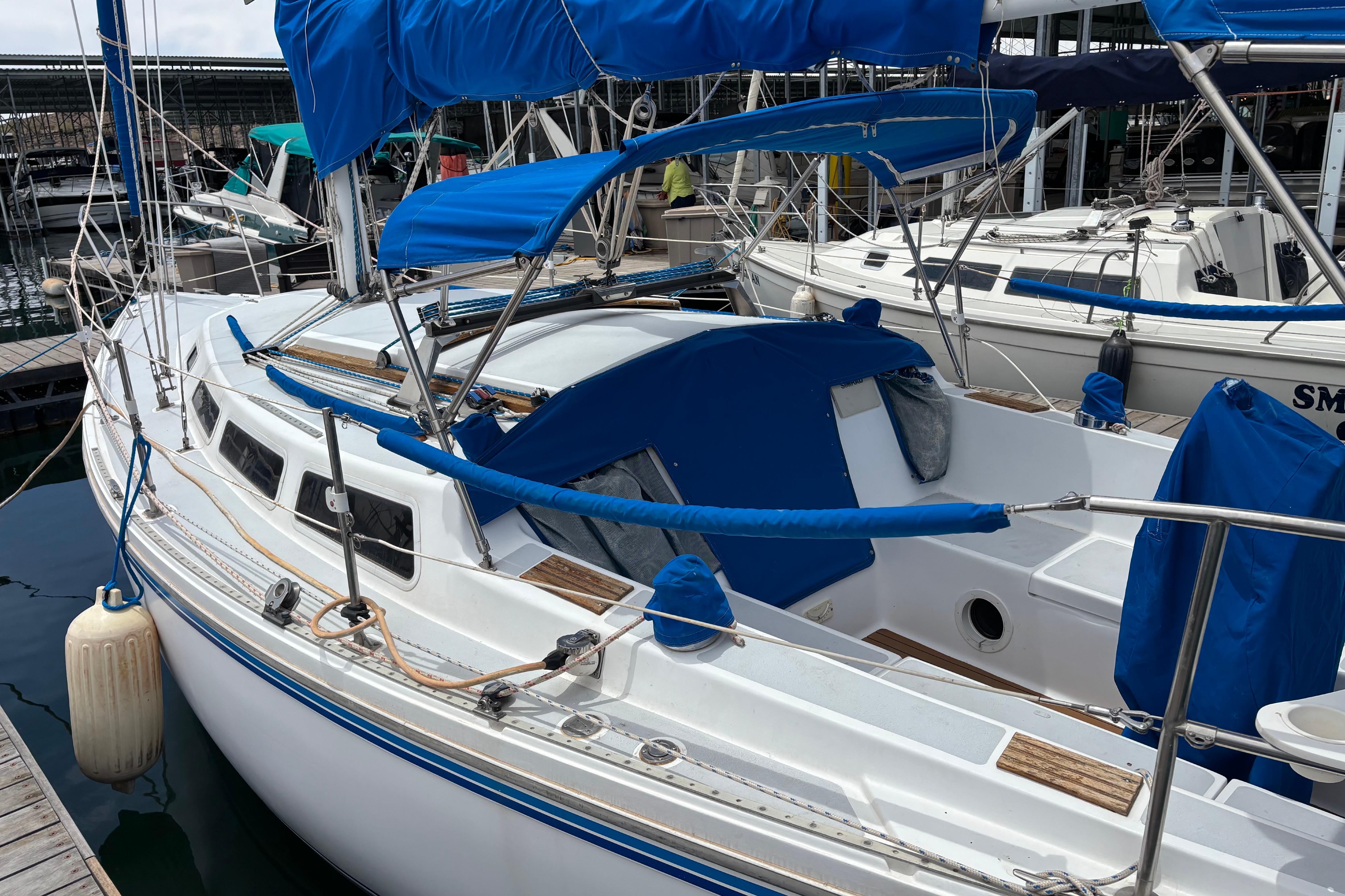 1980 Catalina 30 sailboat docked, featuring blue covers and white hull.