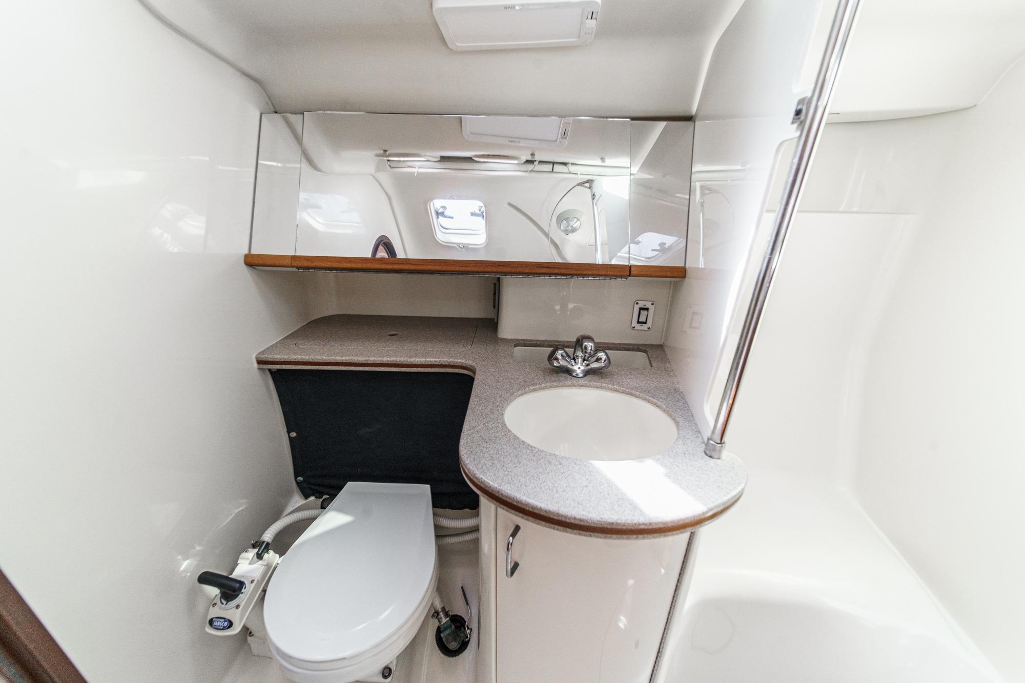 Compact bathroom in a 1996 Hunter 376 yacht, featuring a toilet, sink, and mirror.