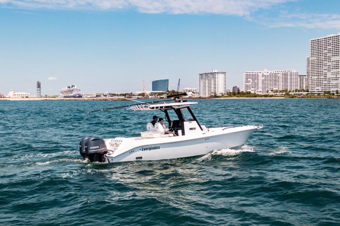 2021 Everglades 295 Center Console boat cruising near city skyline on a sunny day.