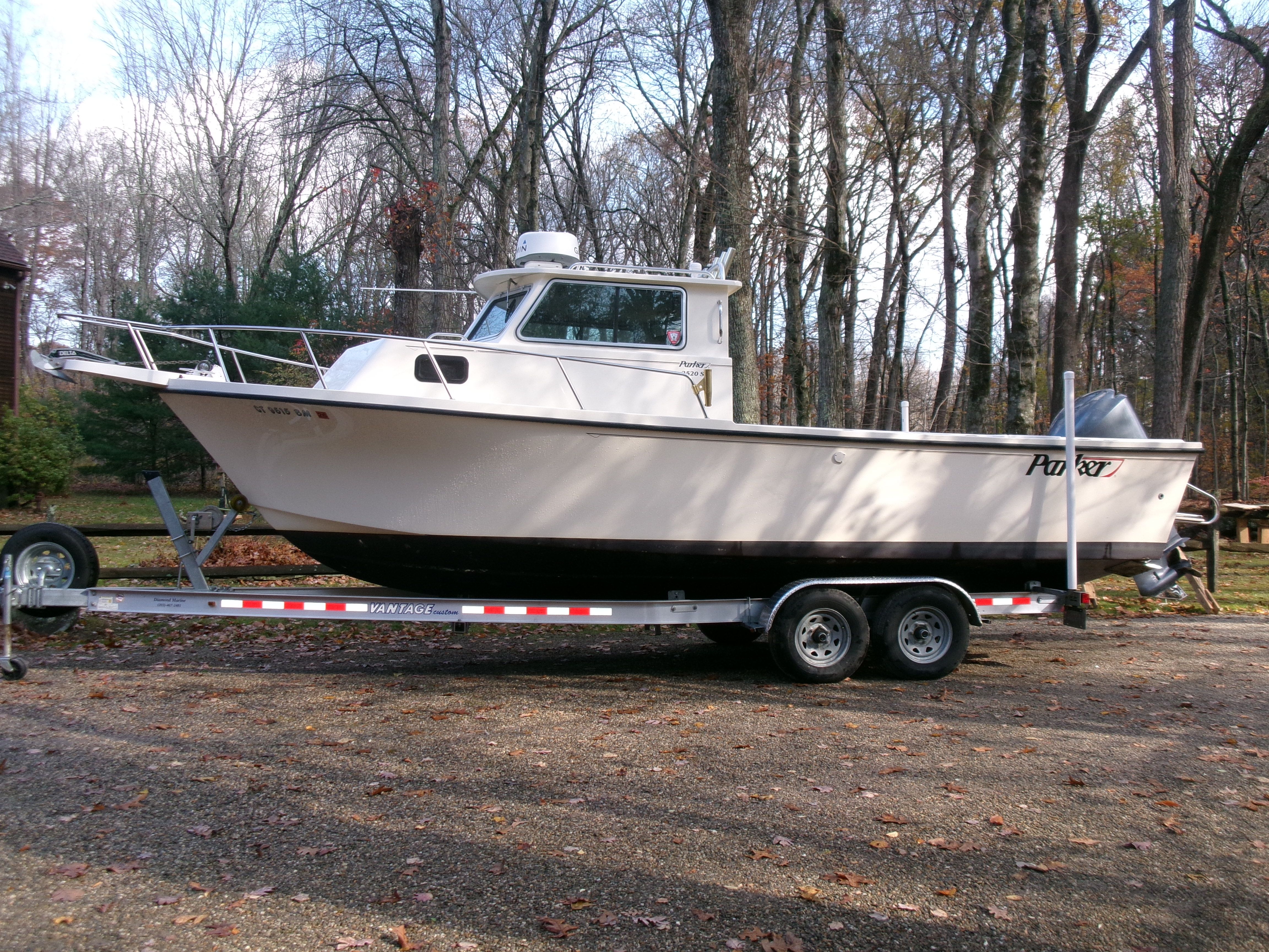 A 2007 Parker 2520 XL Sport Cabin boat on a trailer in a wooded area.