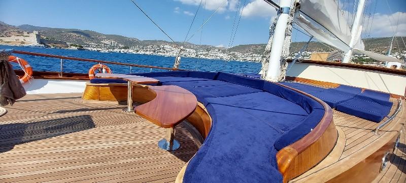 Luxurious 2012 Ketch 37m yacht deck with blue cushioned seating and scenic ocean view.