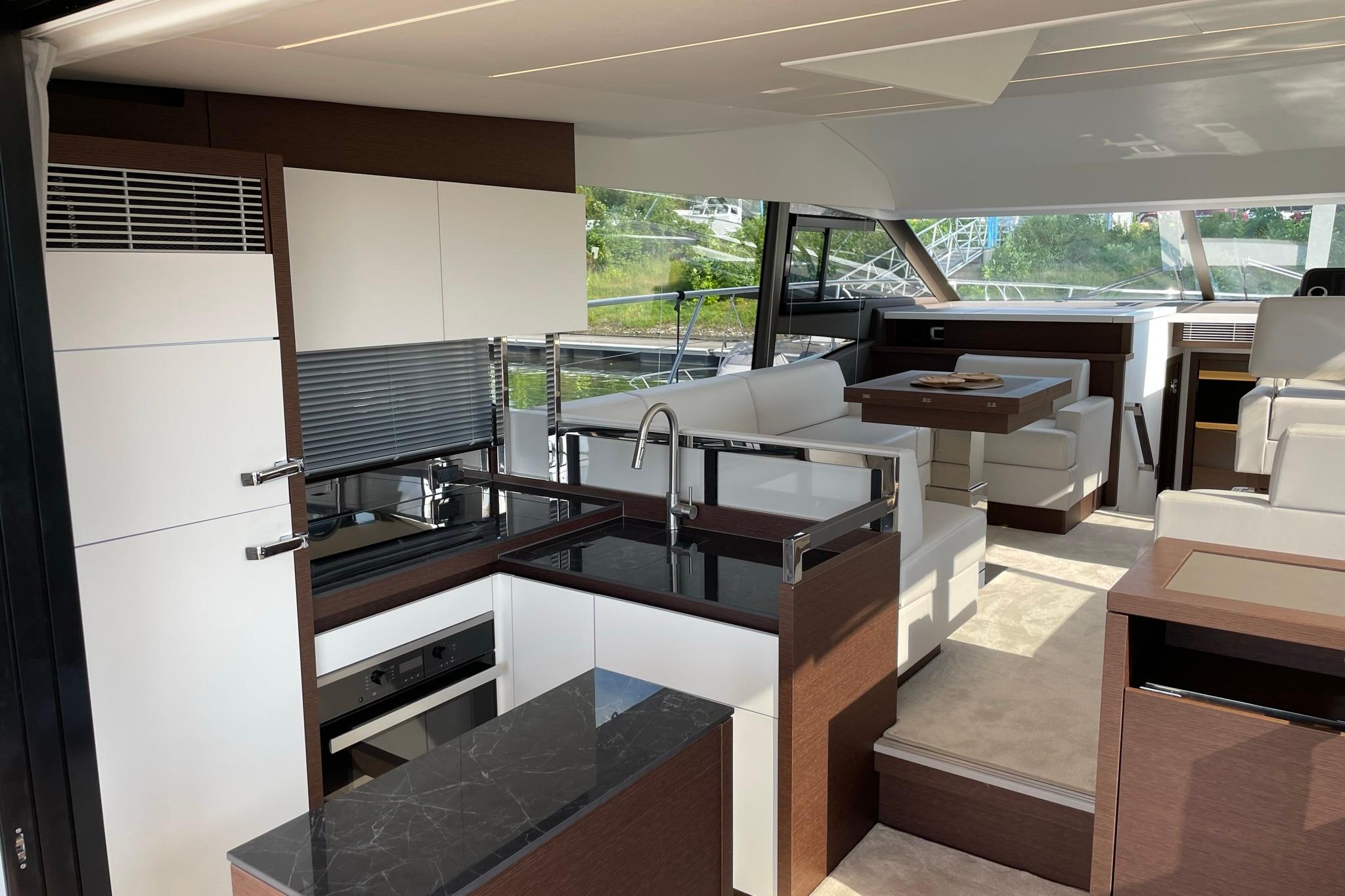 Luxurious interior of a 2022 Prestige 520 yacht with modern kitchen and seating area.