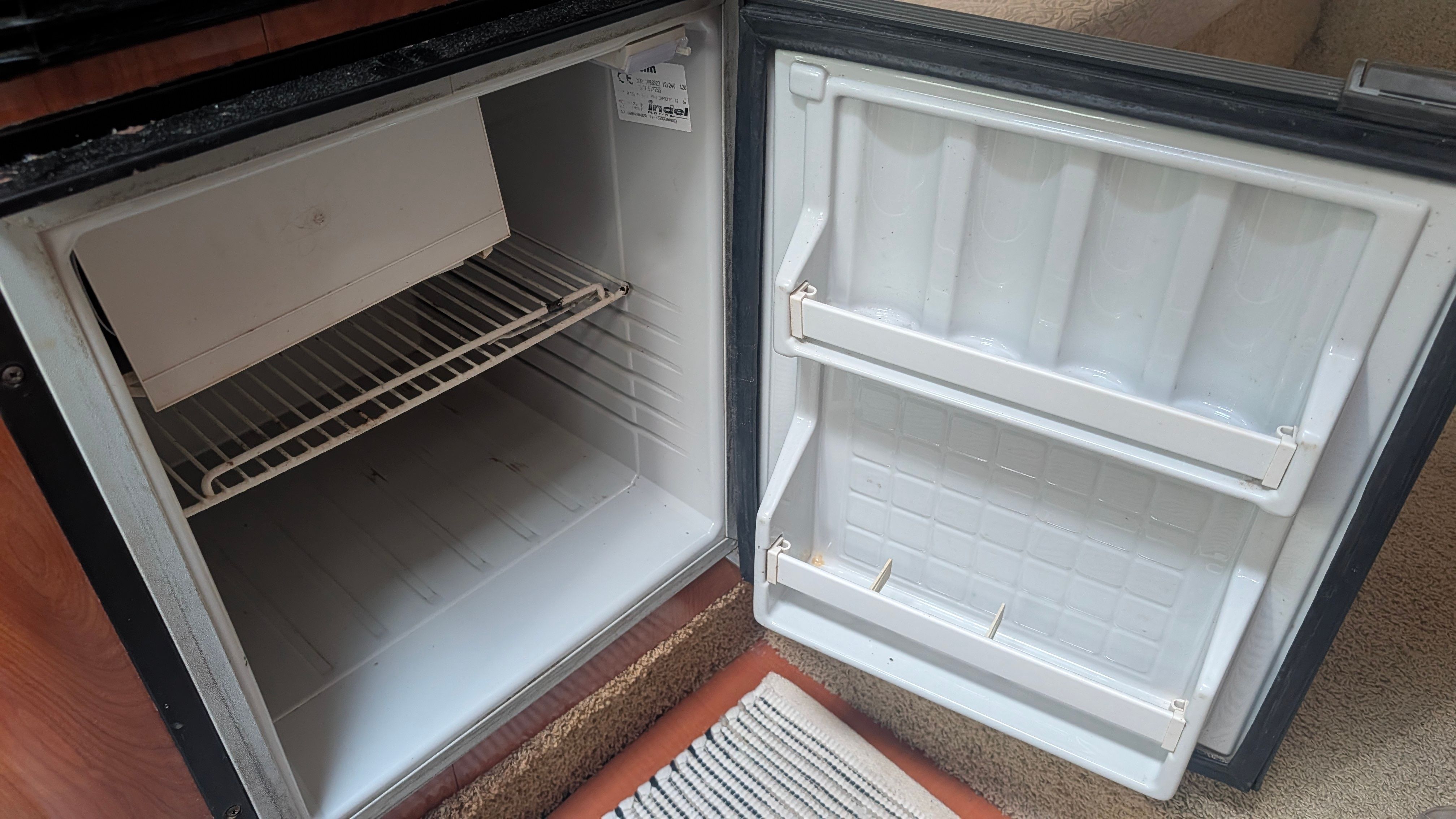 Open fridge in a boat with empty shelves and door compartments.