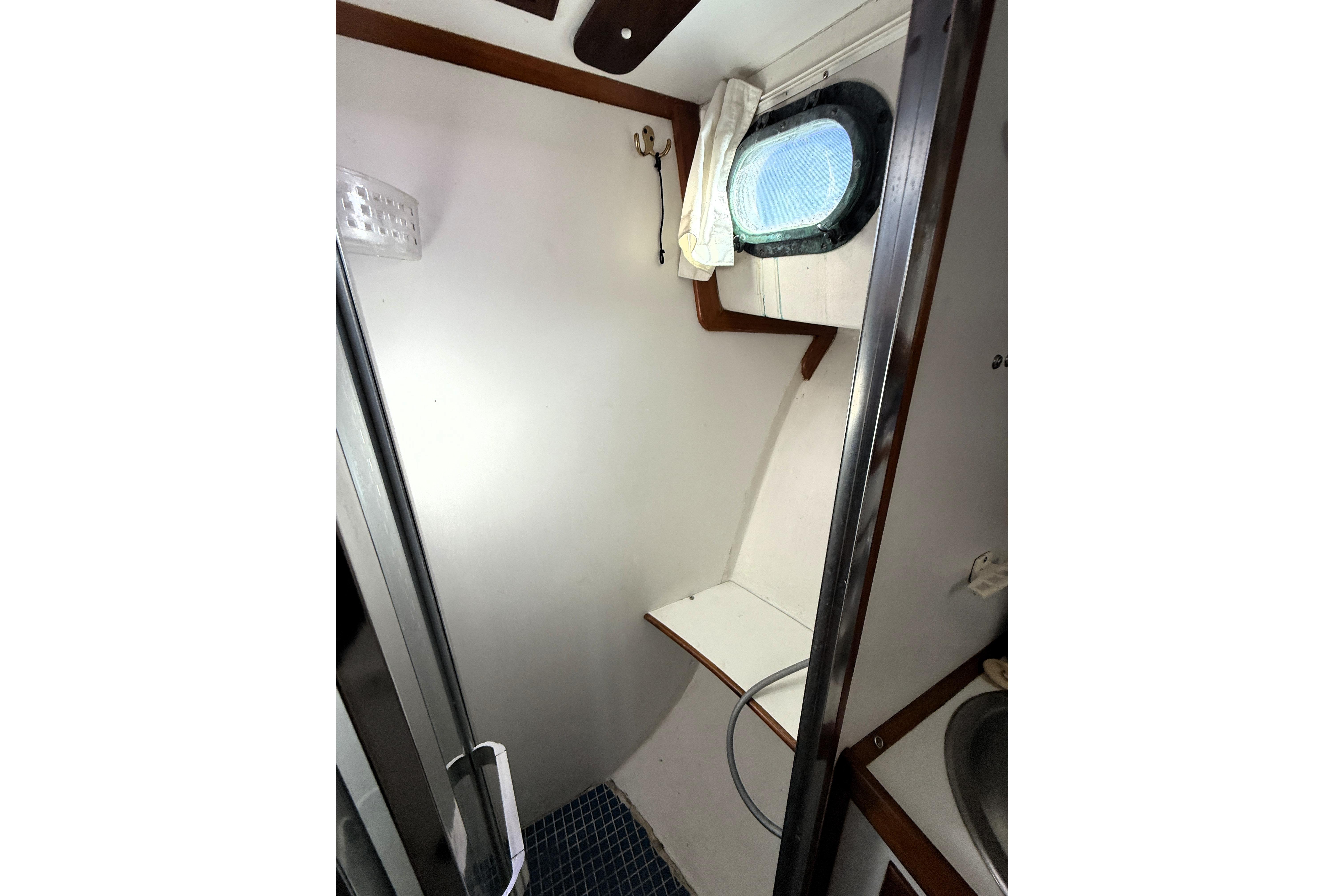 1983 Wilbur 34 Fly Bridge Cruiser bathroom interior with porthole and shower.