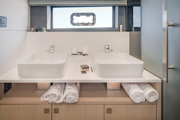 Luxury yacht bathroom with dual sinks, modern design, and rolled towels. Privilege Signature 650, 2025.