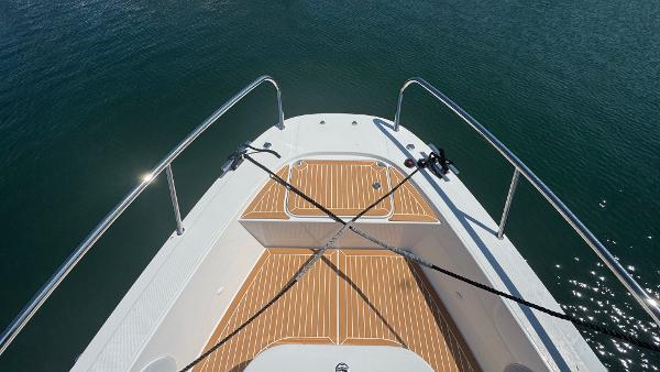 Bow of 2025 Nimbus T11 boat with teak decking on calm water.