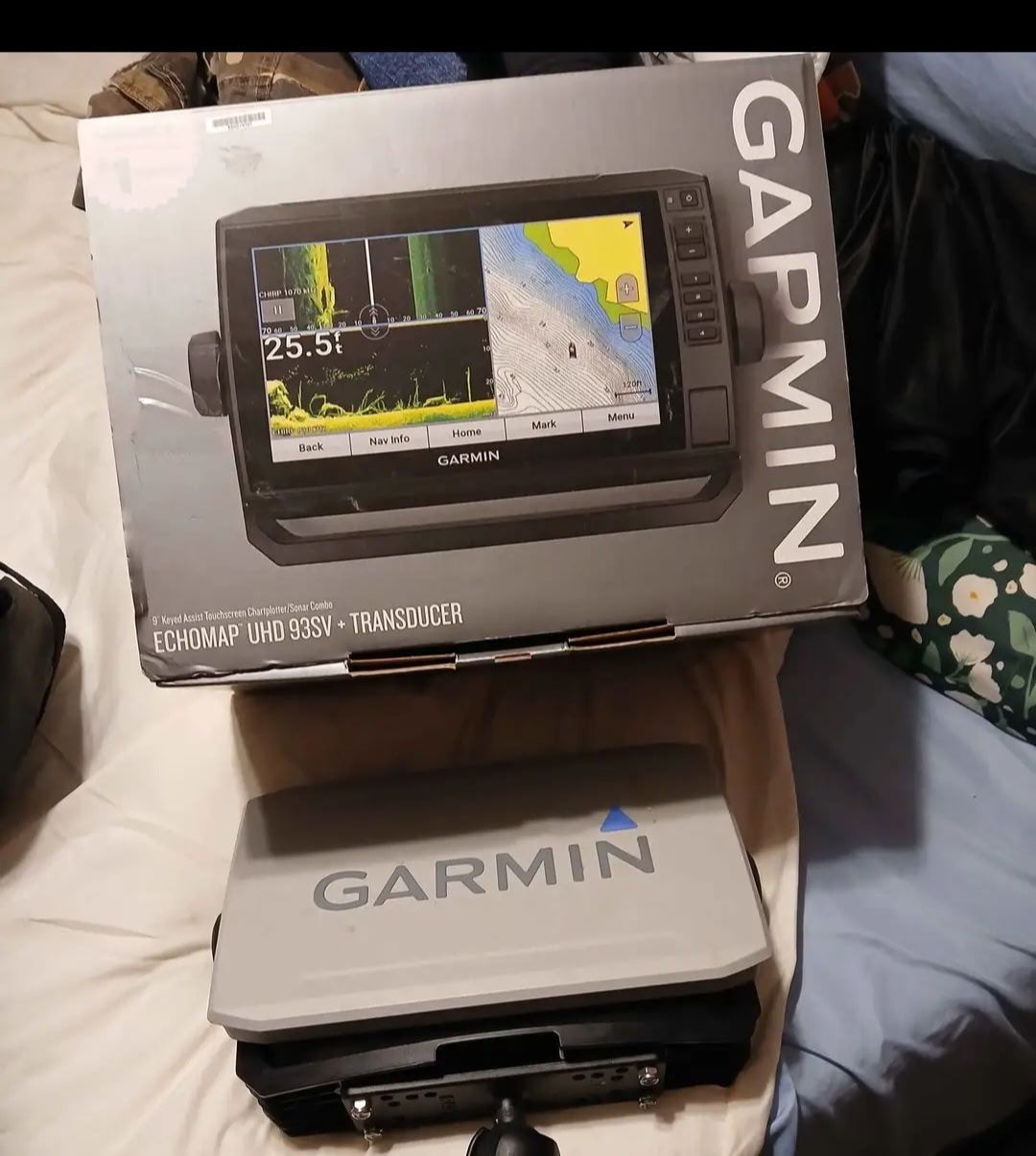 Garmin Echomap UHD 93sv transducer box on a bed, with a Garmin case beside it.
