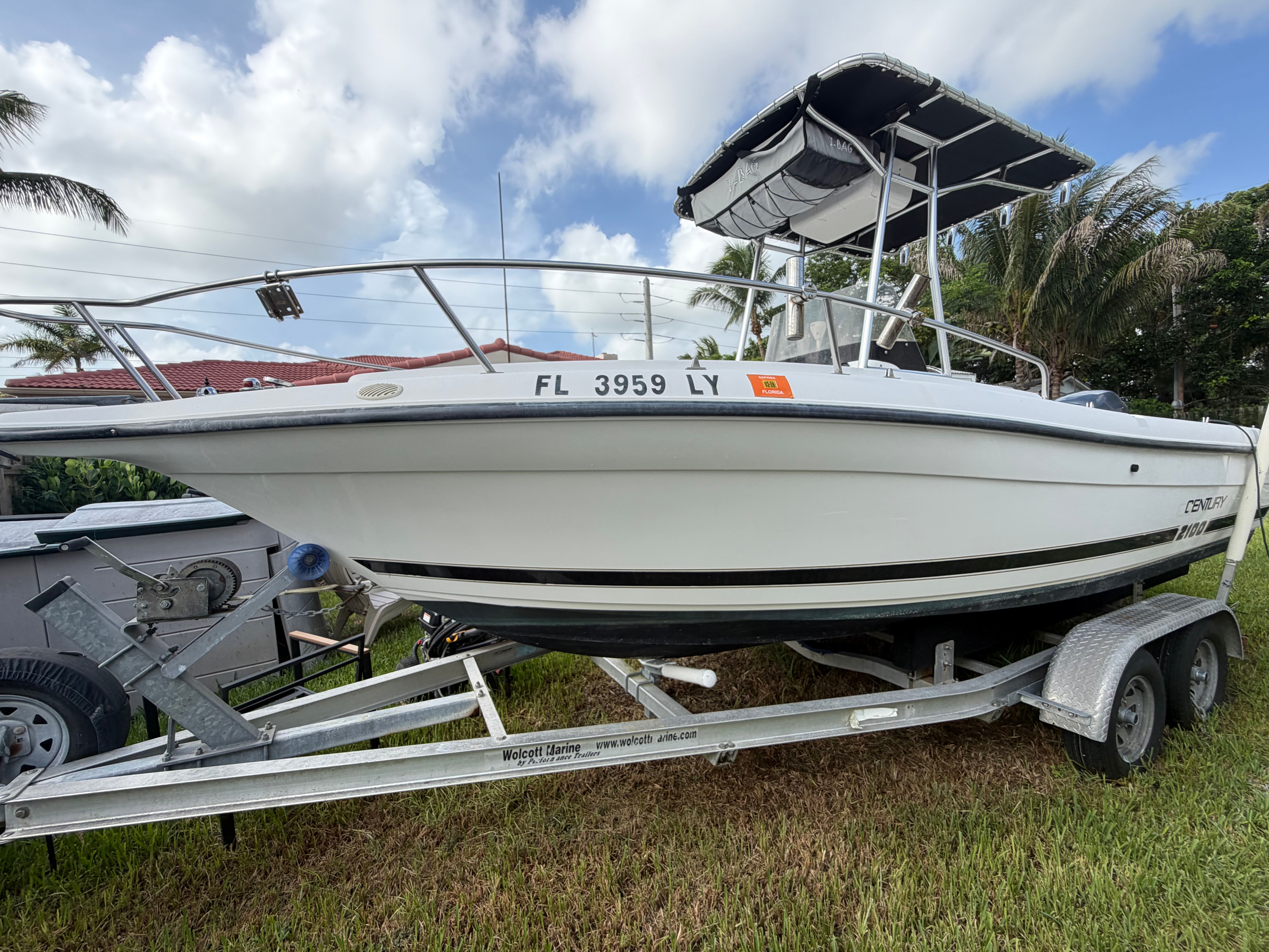 A 2001 Century 2100 Center Console boat on a trailer, surrounded by palm trees.