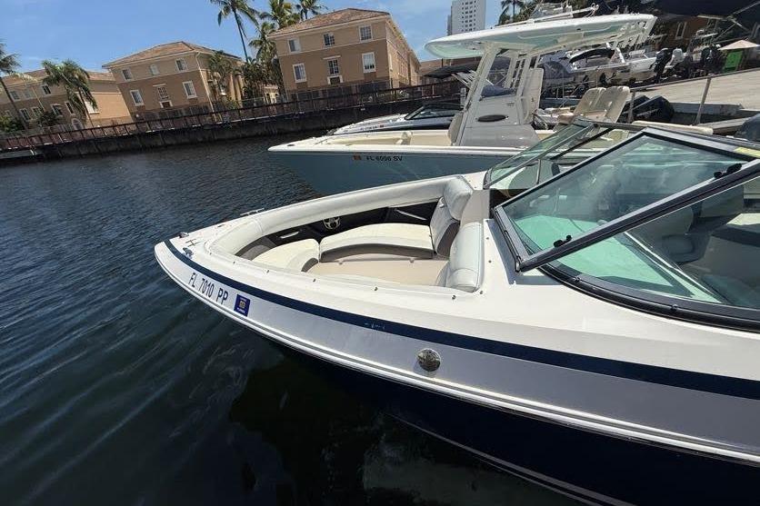 2014 Regal 2500 Bowrider boat docked in marina, surrounded by buildings and palm trees.