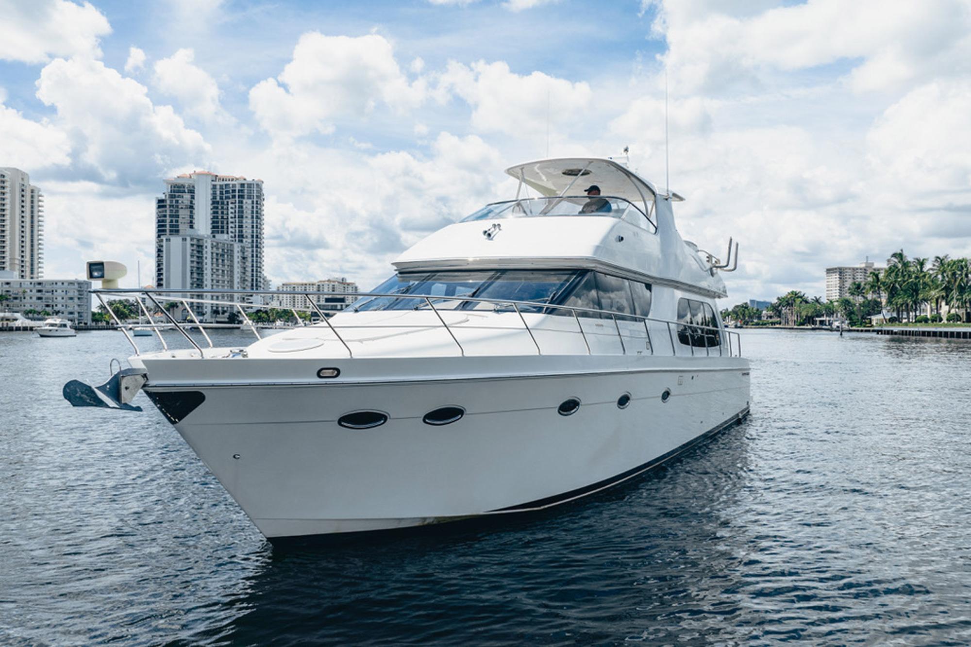 2005 Carver 56 Voyager yacht cruising on a sunny day with cityscape background.