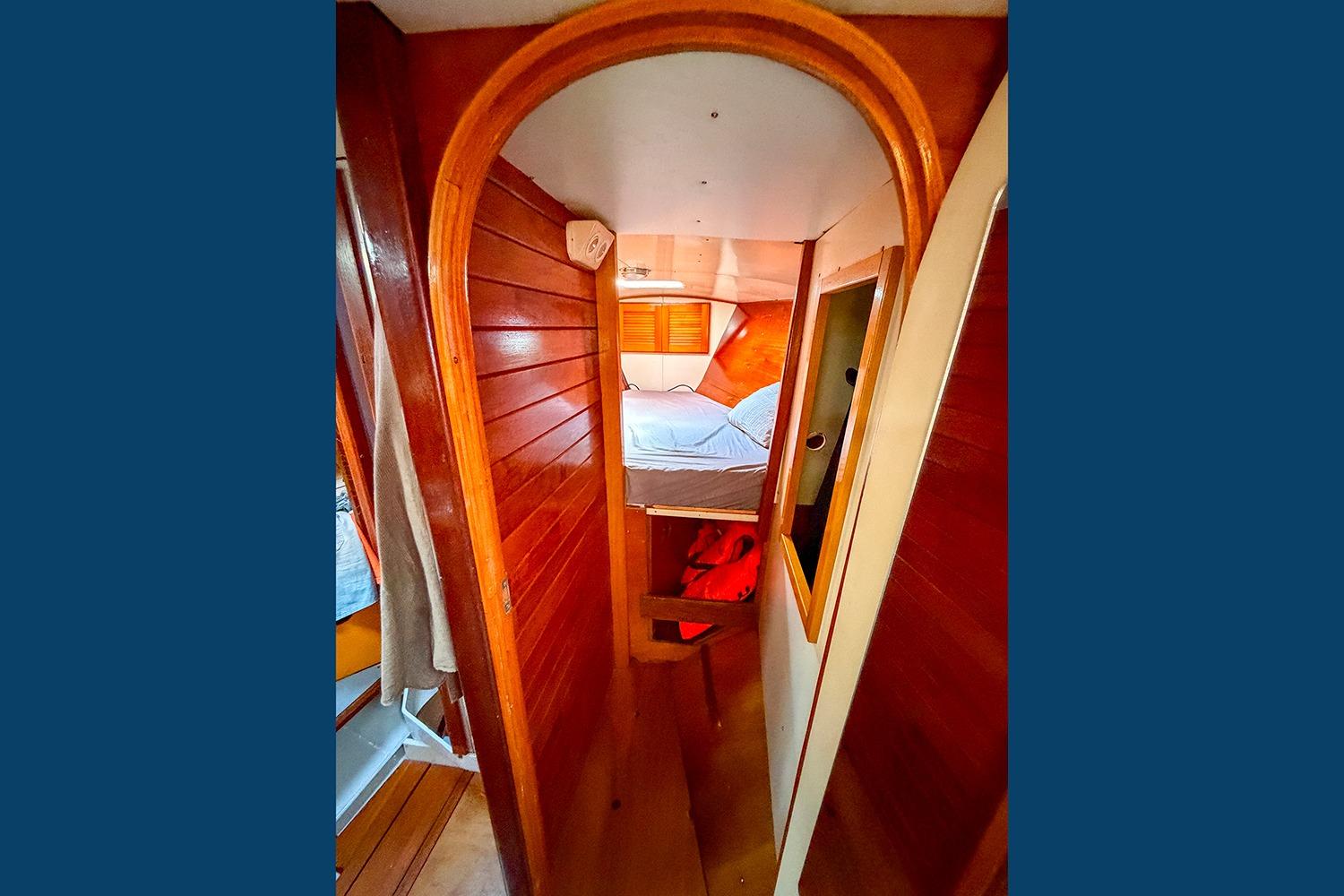 Cozy wooden cabin interior of 1982 Custom Oneiros 43 sailboat, featuring a bed and warm lighting.