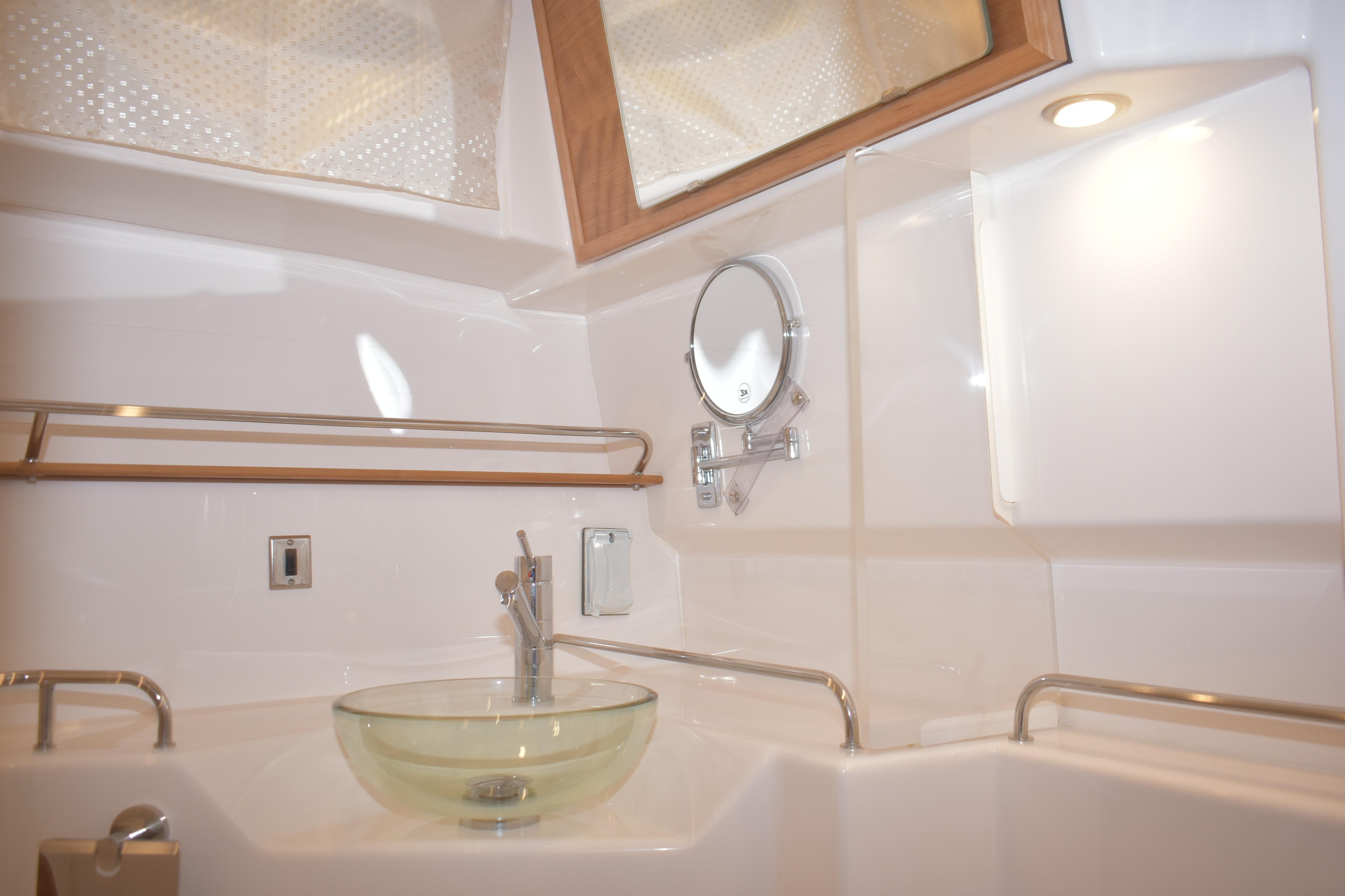 Modern bathroom interior of 2026 Cutwater C-32 CB yacht with glass sink and porthole.