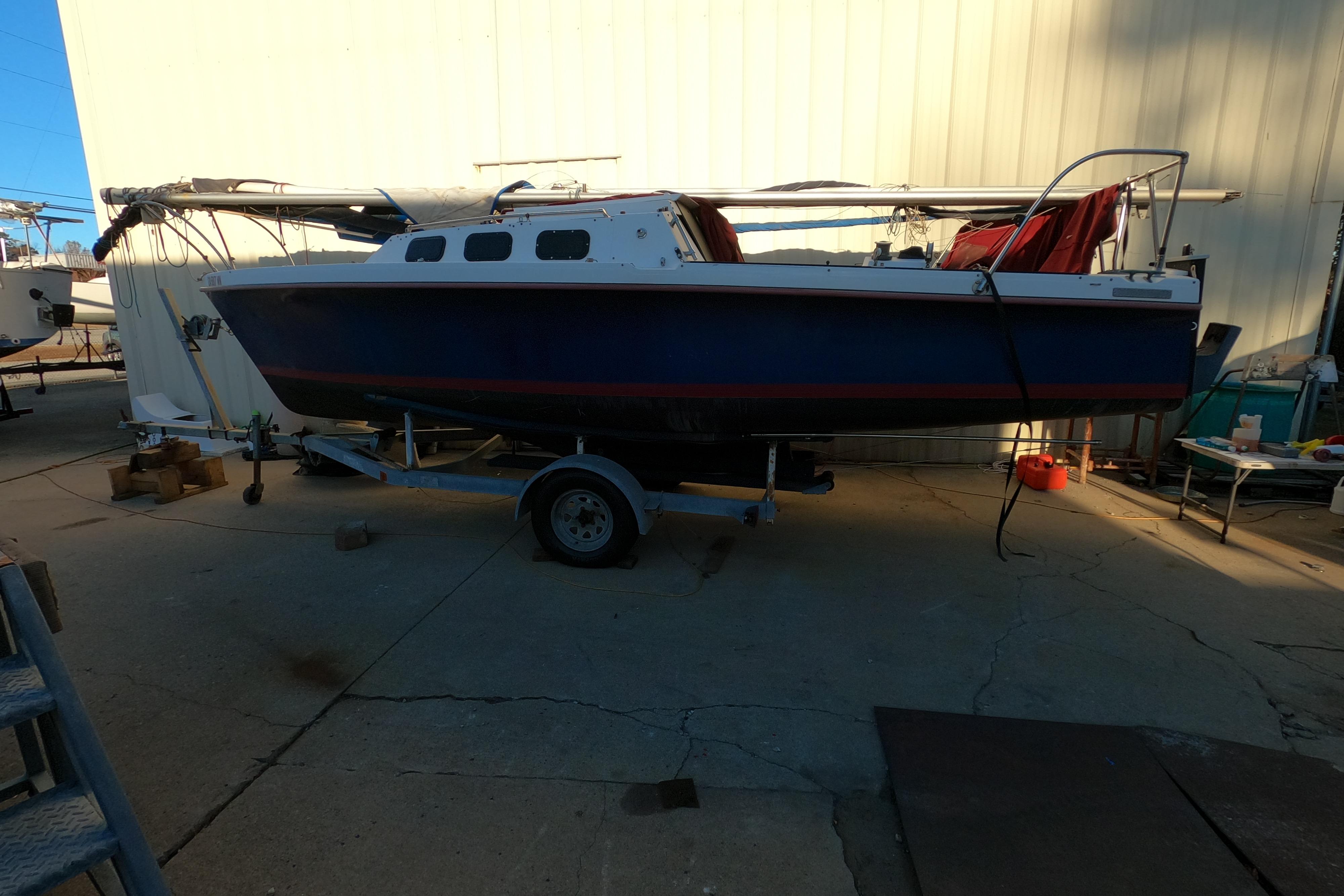 1986 Rhodes 22 sailboat on trailer, parked outdoors near a building.