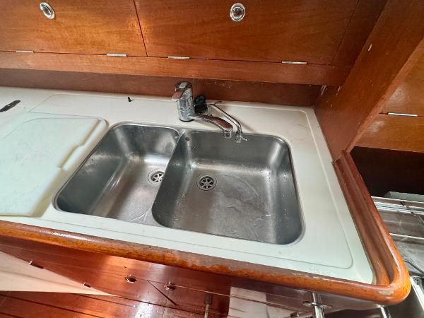 Galley sink in 1996 Beneteau Oceanis 40 CC yacht with wooden cabinetry.