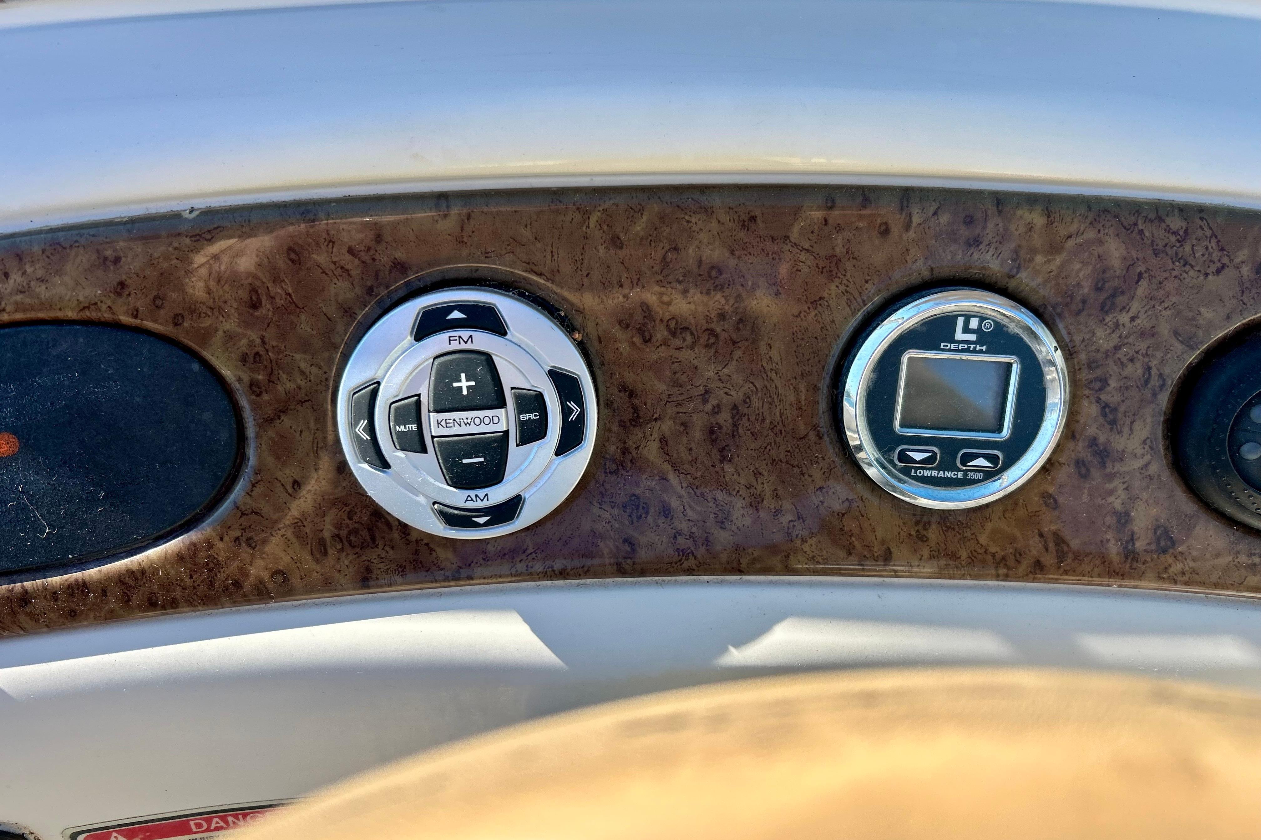 Dashboard controls of a 2000 Sea Ray 240 Sundeck boat, featuring Kenwood audio and Lowrance depth gauge.