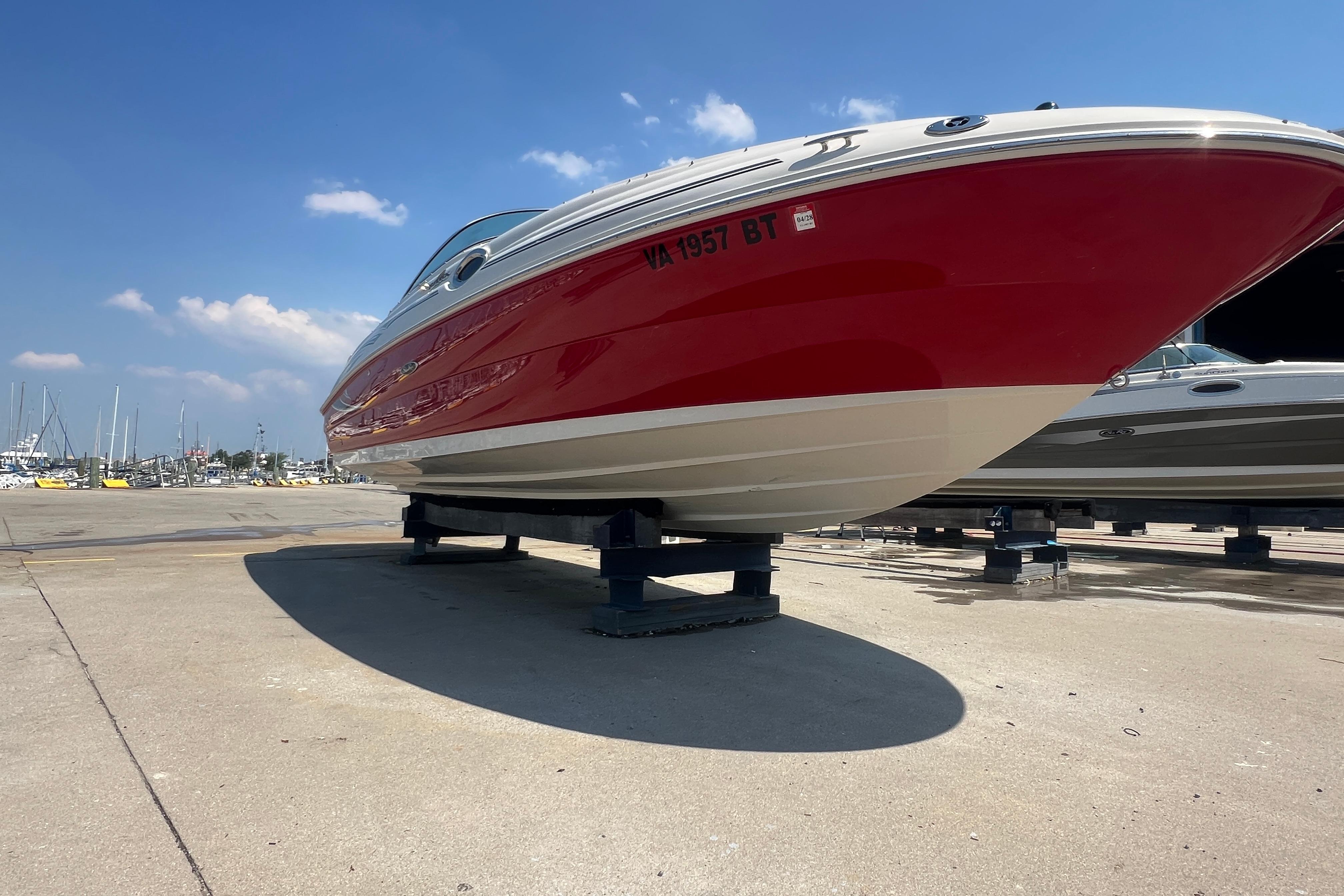 2005 Sea Ray 240 Sundeck boat with red hull on dry dock under blue sky.