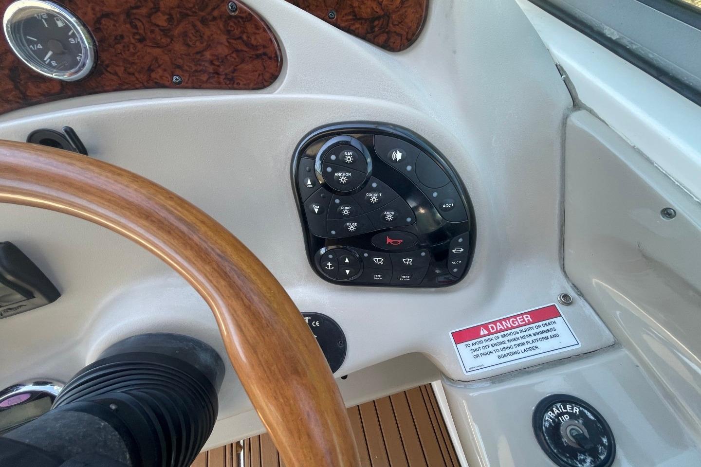 Control panel of a 2008 Sea Ray Sundancer 280 boat with wooden steering wheel.