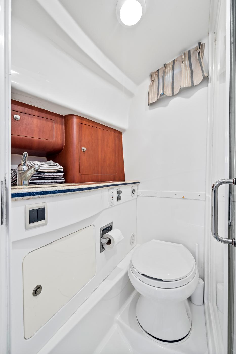2006 Intrepid 377 WA boat bathroom with toilet, sink, and wooden cabinetry.