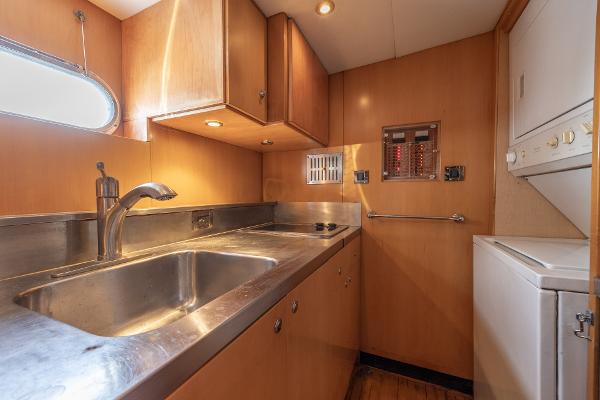 Compact kitchen area in a 2001 Grand Harbour 76 yacht with stainless steel sink and wooden cabinets.