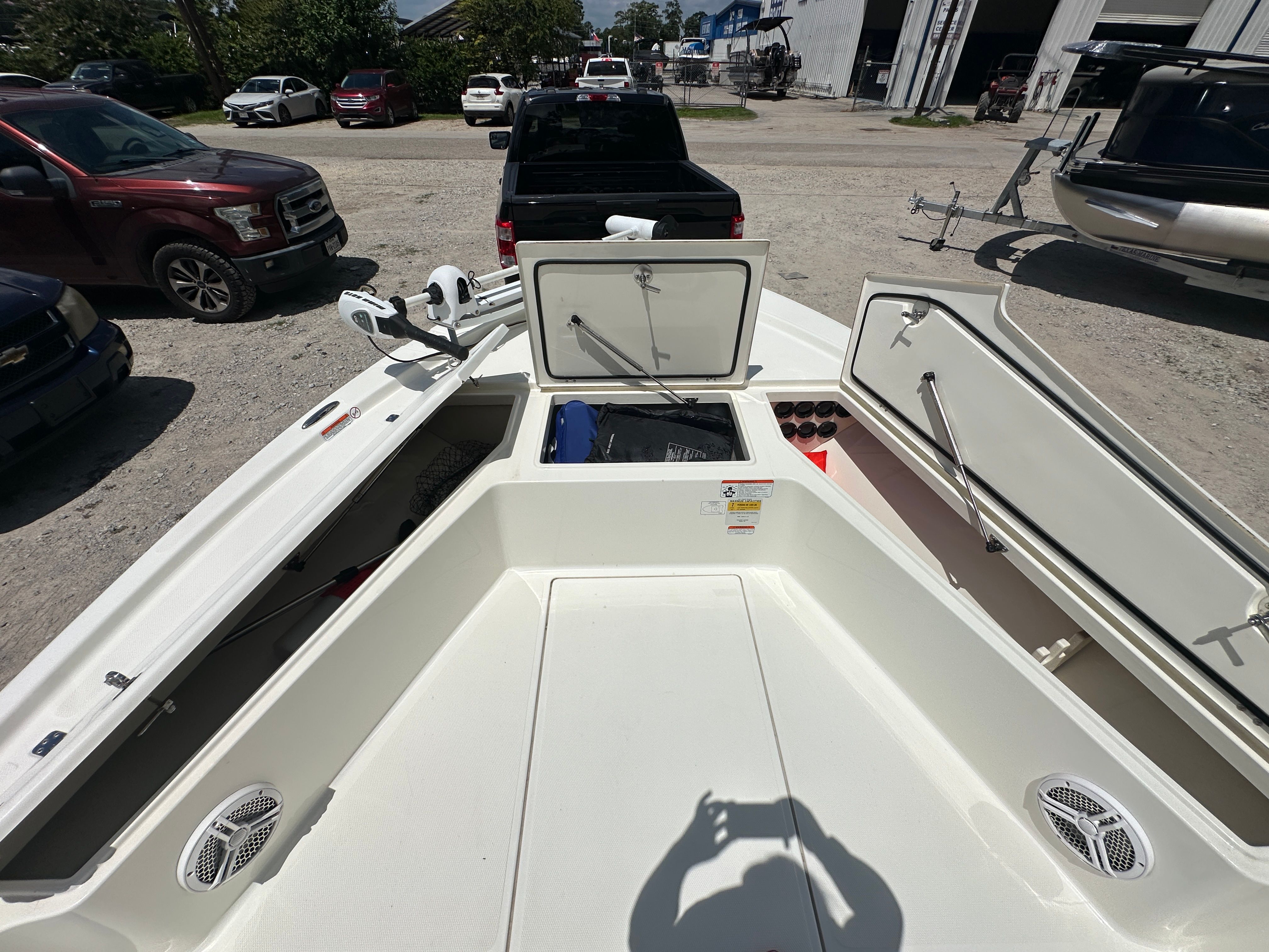 2014 Mako 21 LTS boat with open storage compartments in a parking lot.