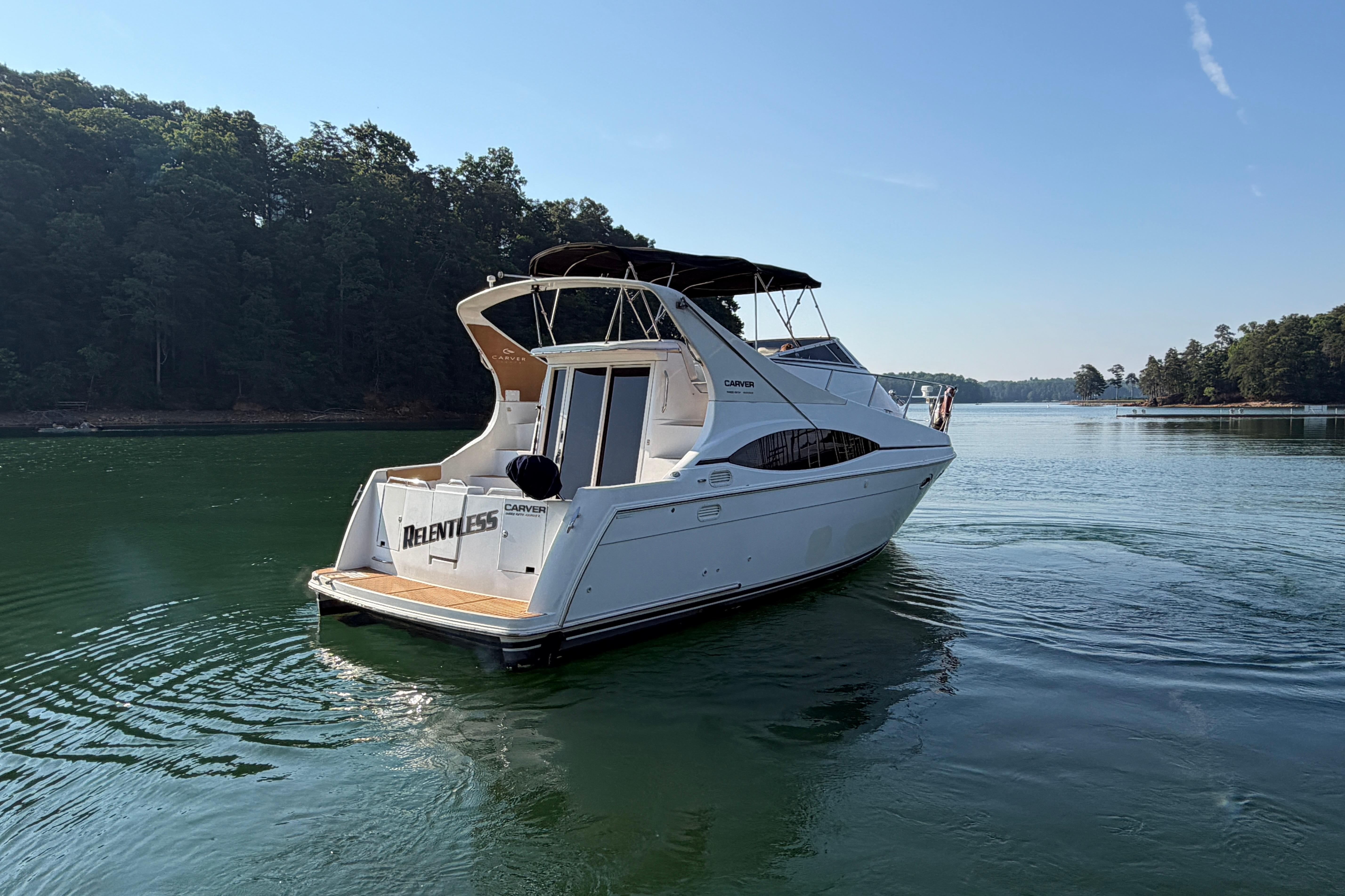 2003 Carver 350 Mariner yacht on a serene lake with forested shoreline.