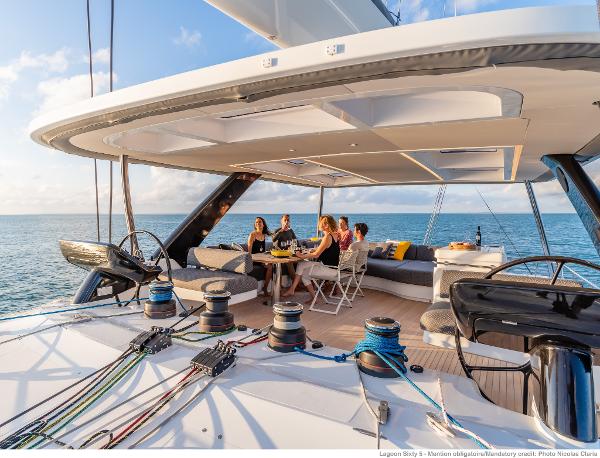 Luxurious Lagoon SIXTY 5 yacht deck with people dining, 2025 model, ocean view.
