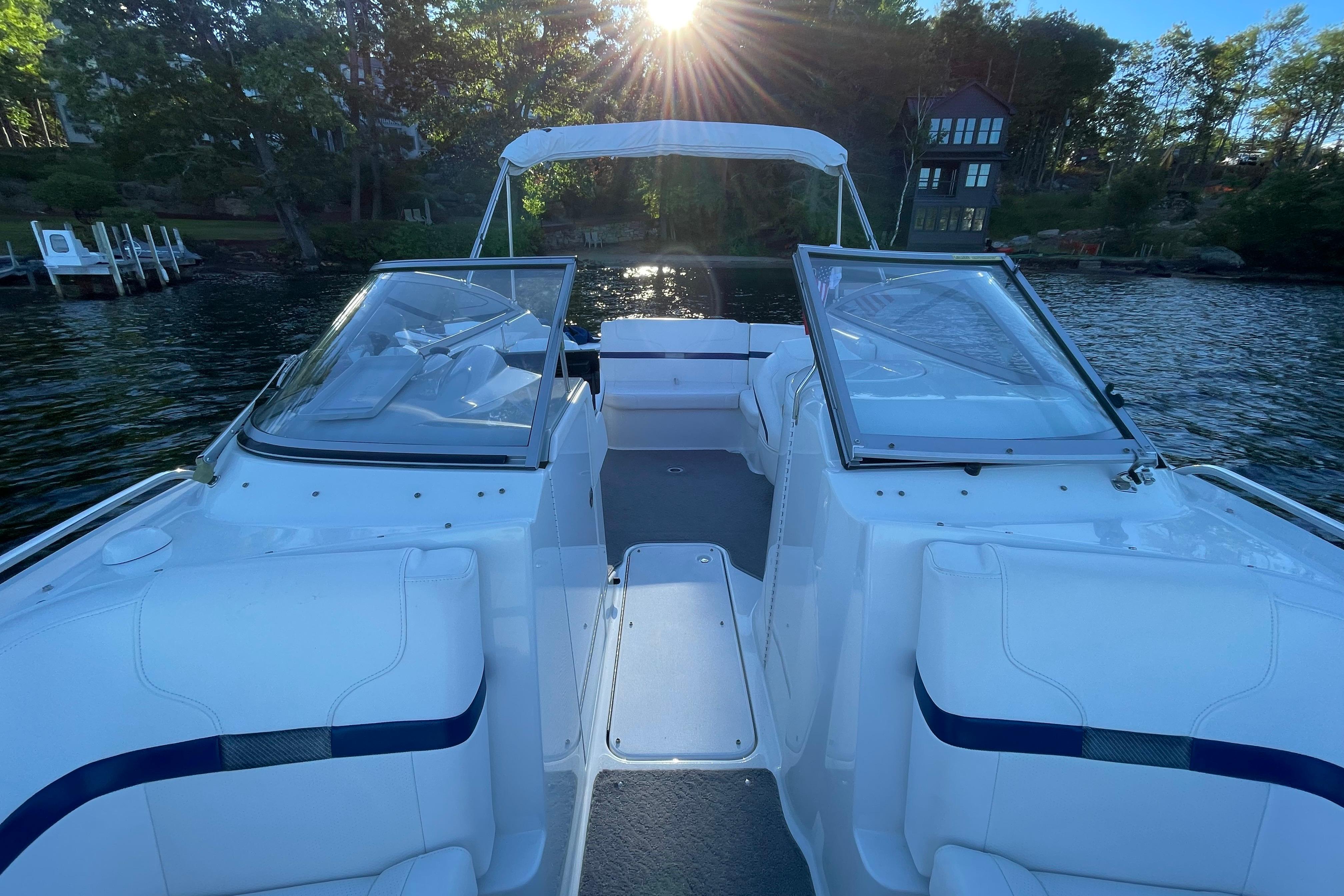 2005 Formula 240 Bowrider boat on a serene lake with sunlit trees.